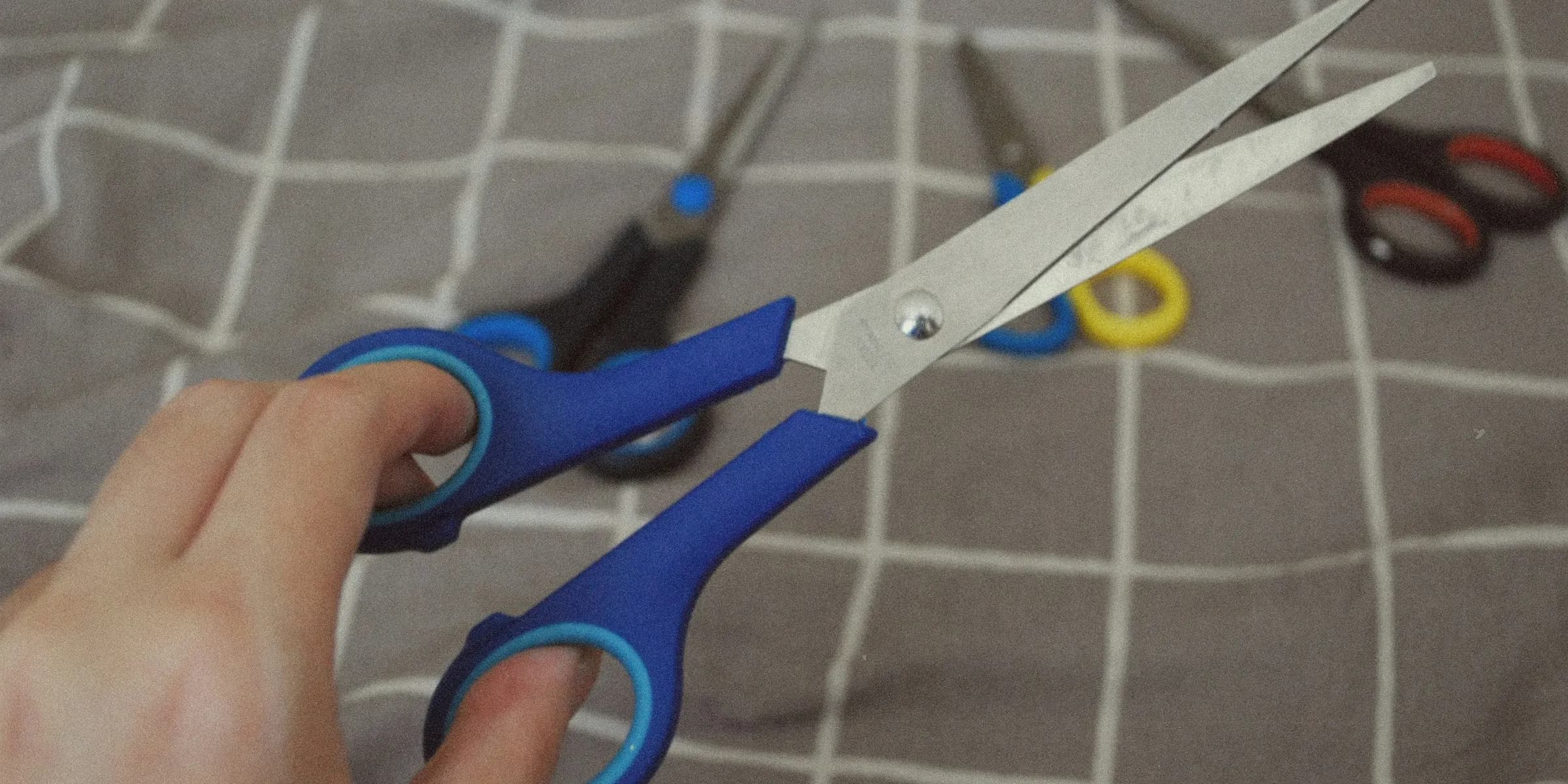 A person holding a pair of scissors on a bed