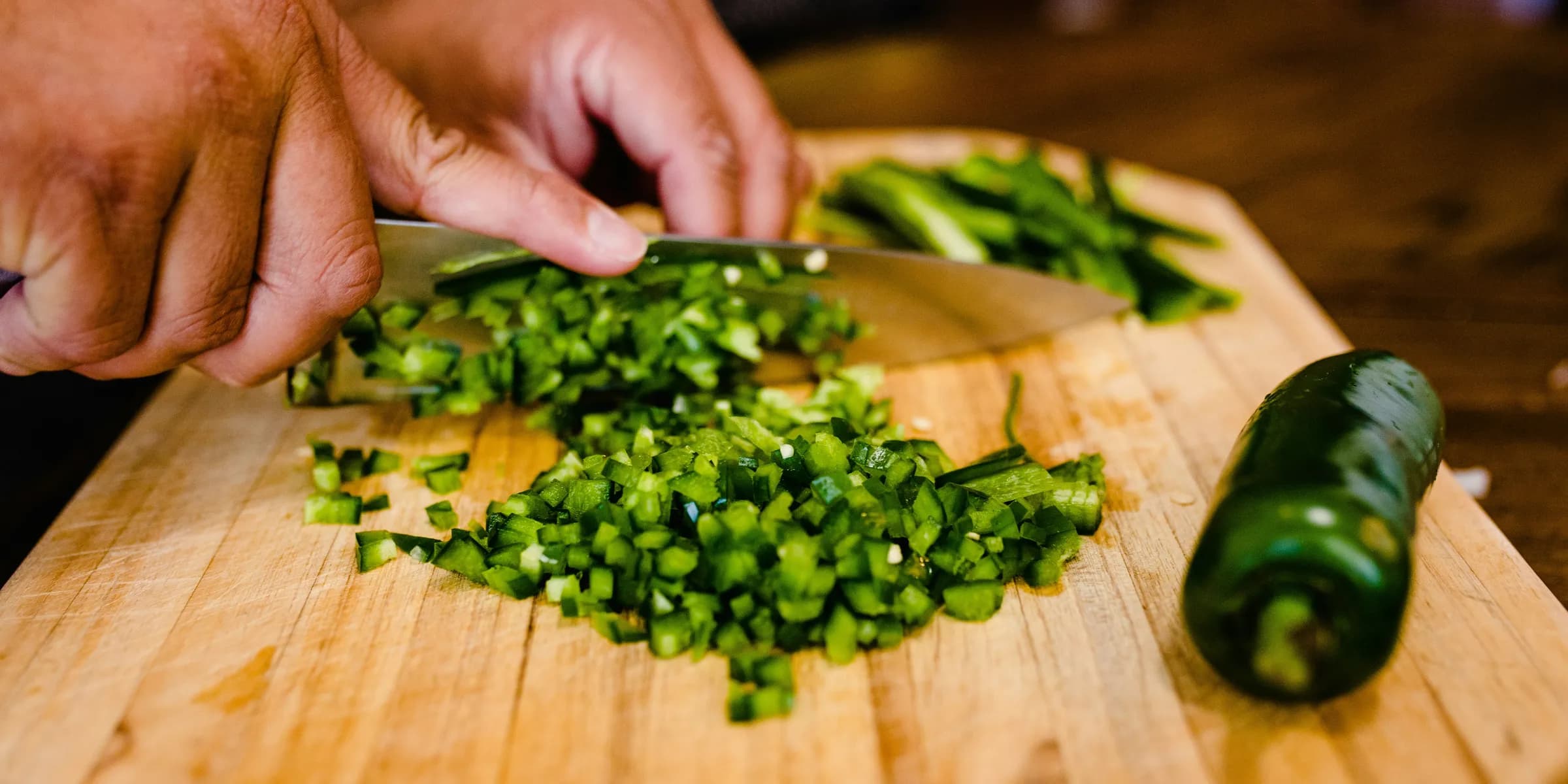 a person cutting up green peppers on a cutting board