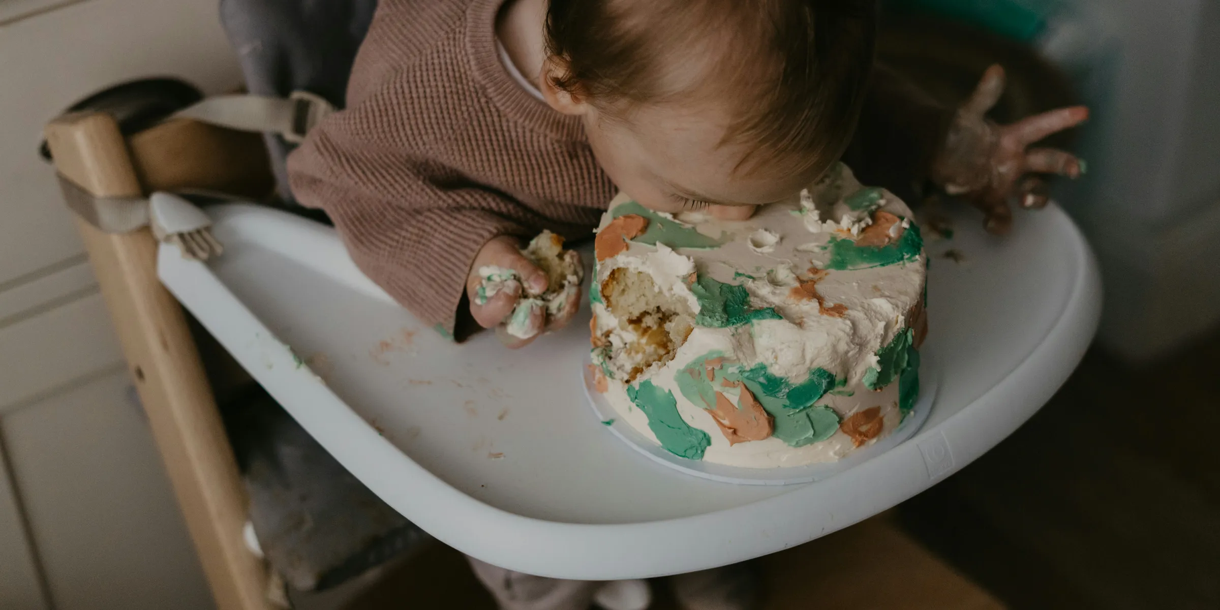 a baby in a high chair eating a cake