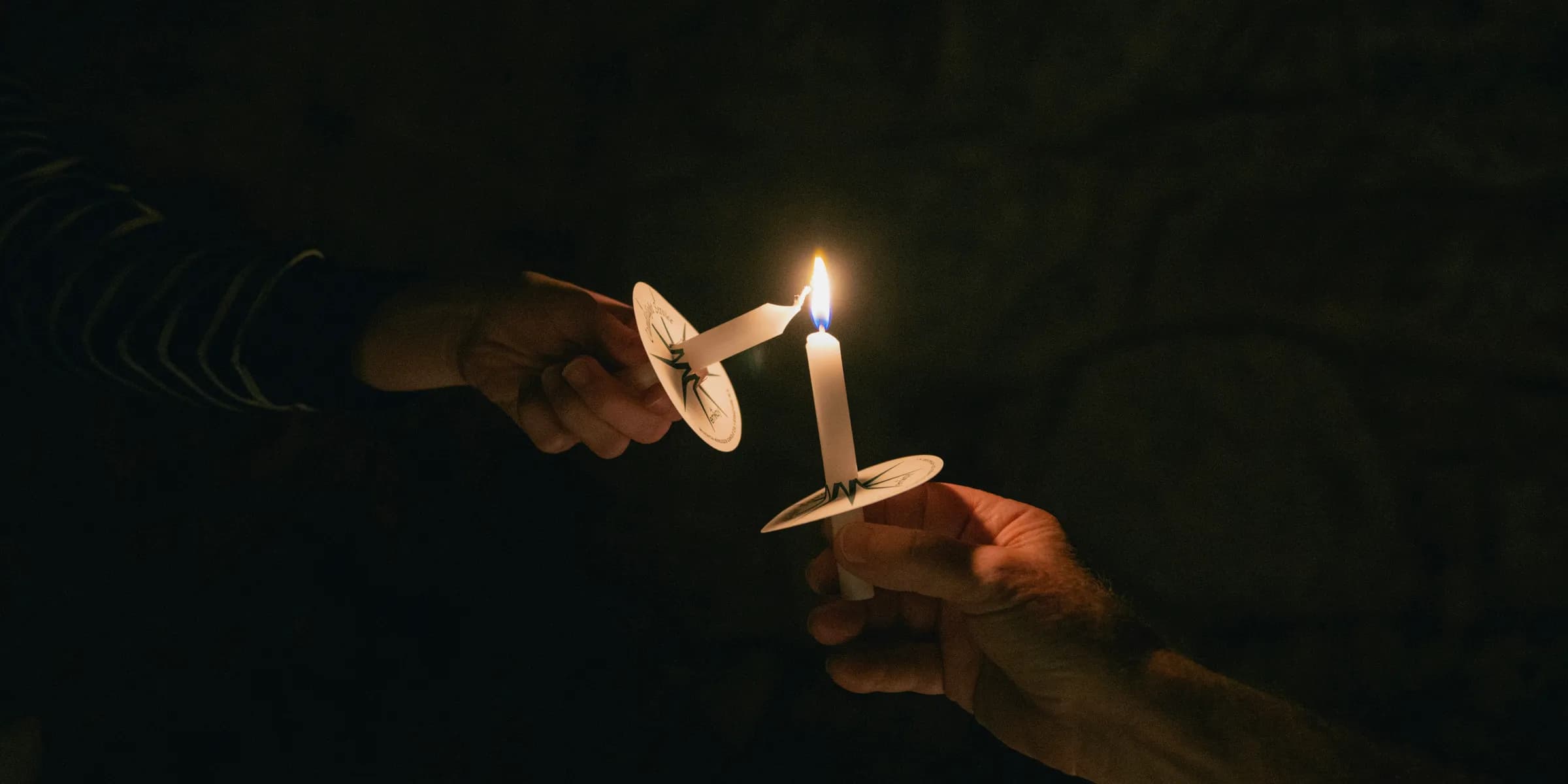 two people holding a candle in their hands