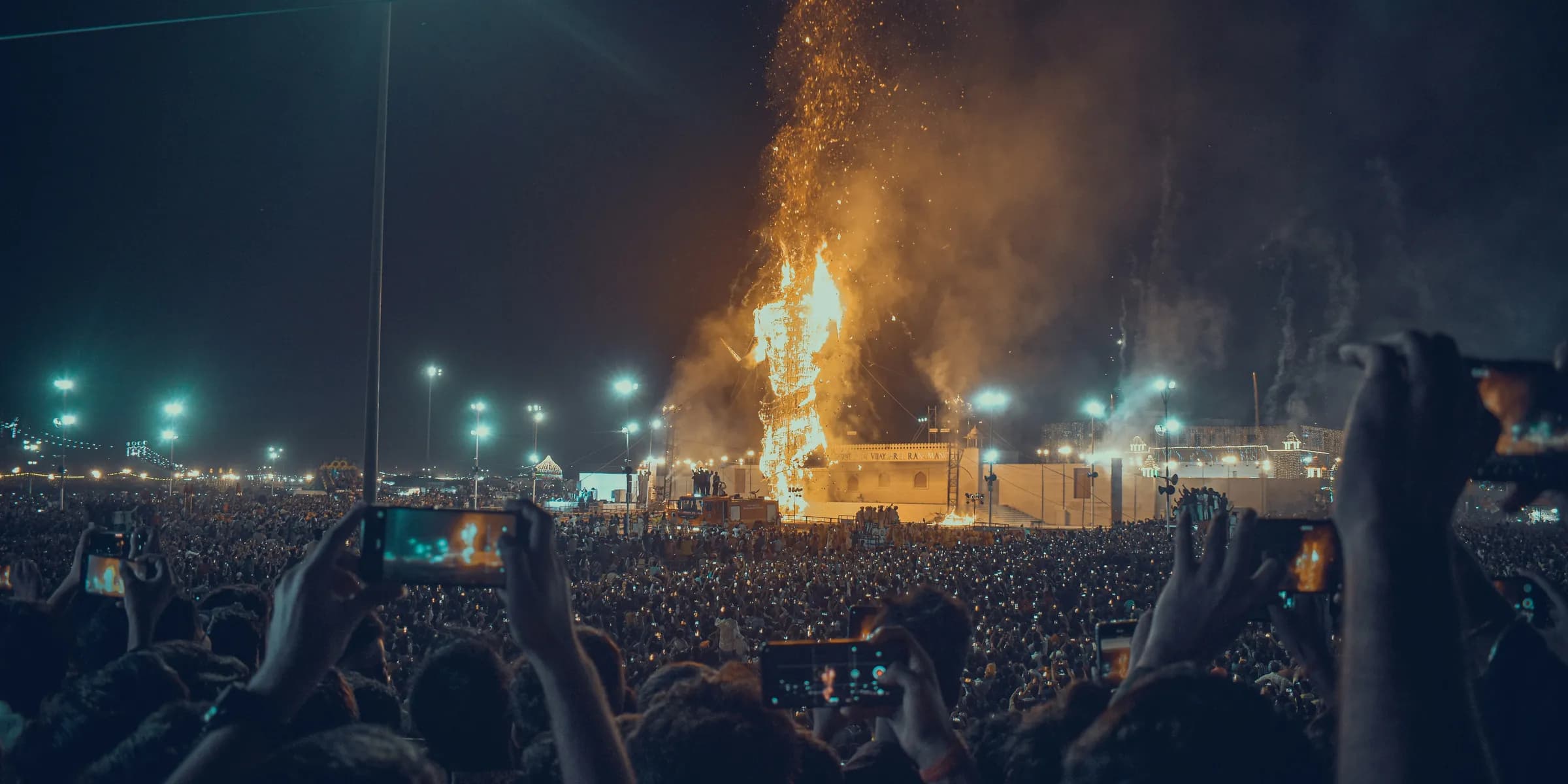 a crowd of people watching a stage with fireworks in the background