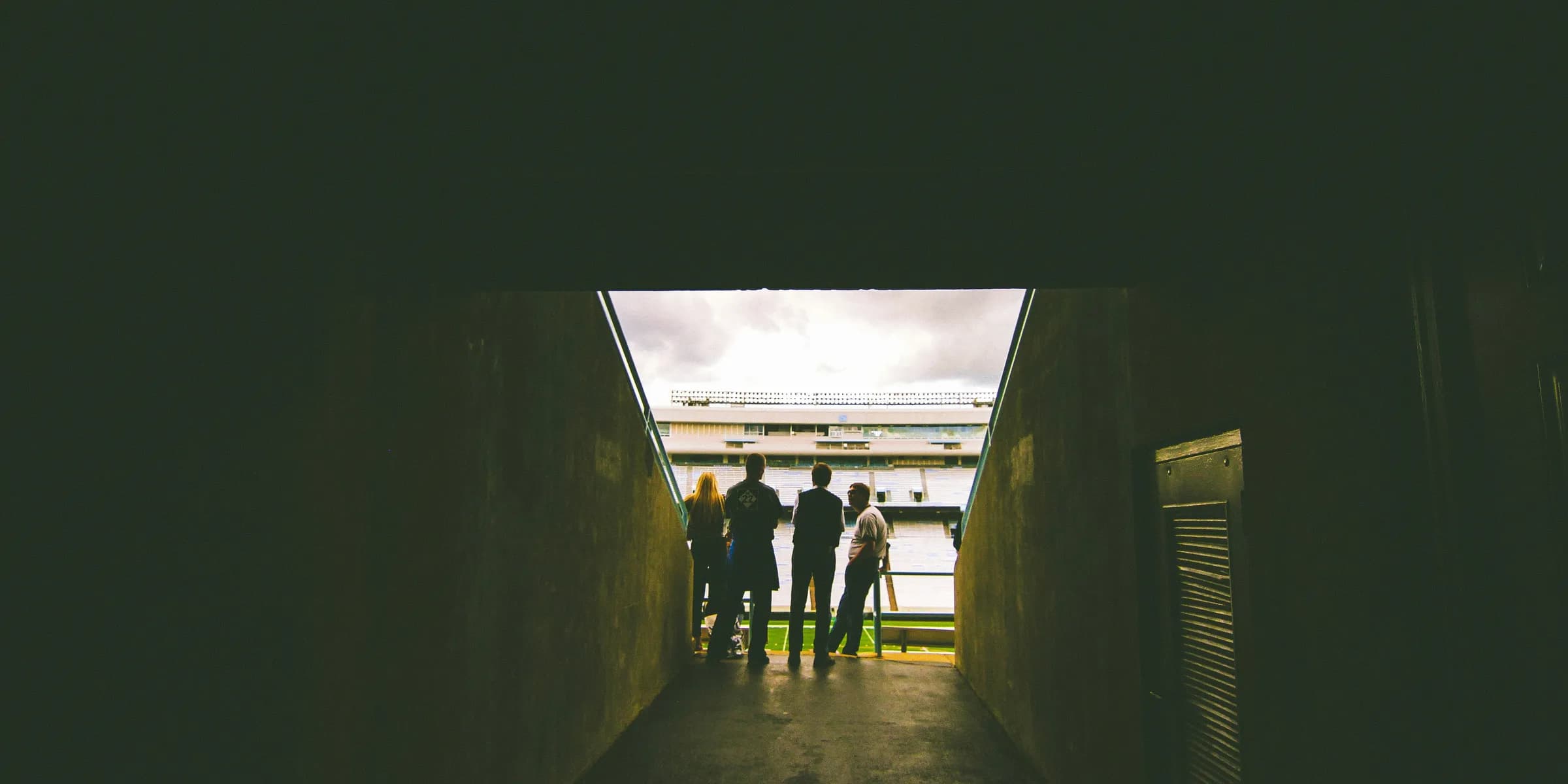 four people standing near gray concrete wall during daytie