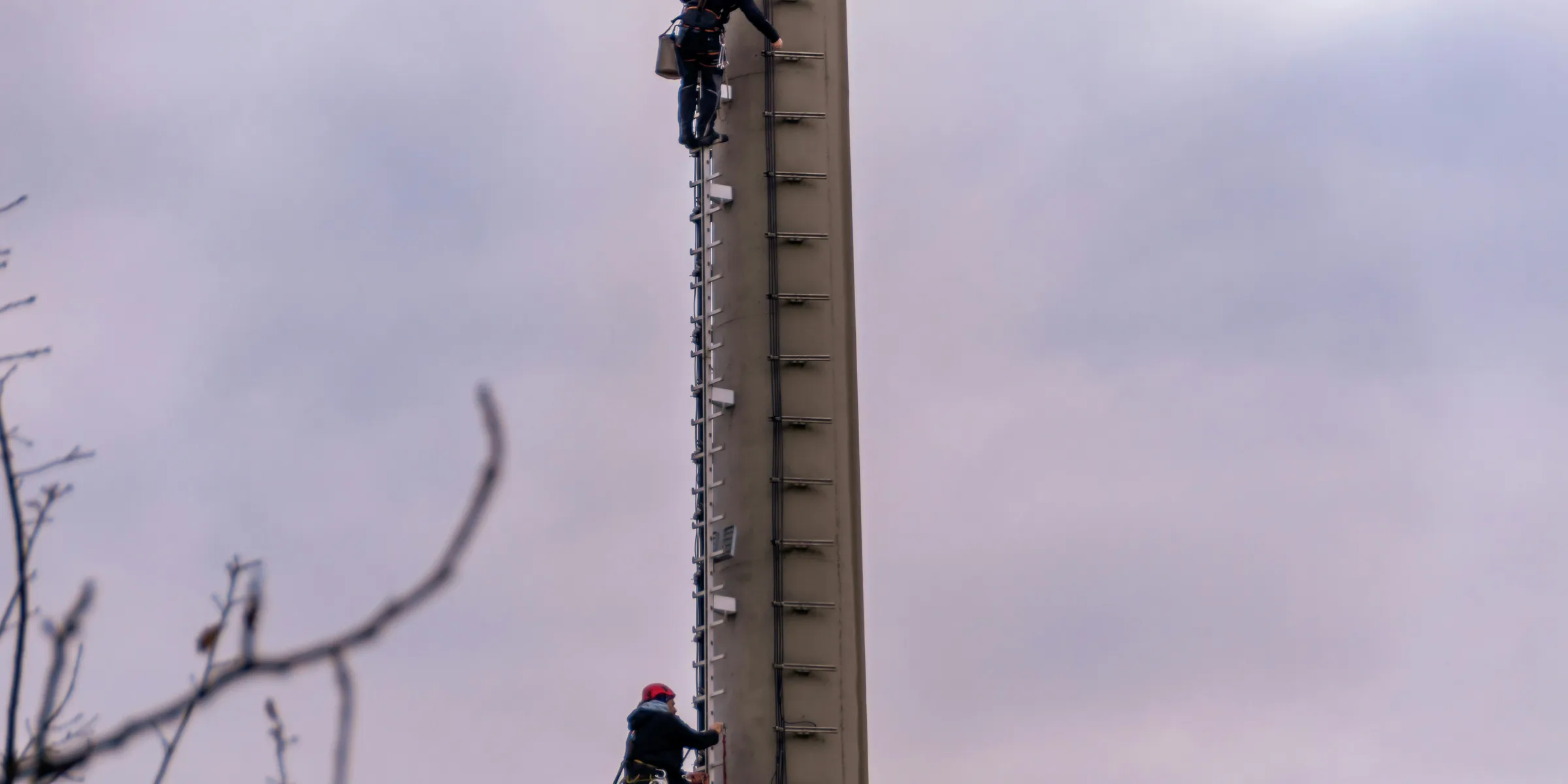Workers climbing a tall communication tower