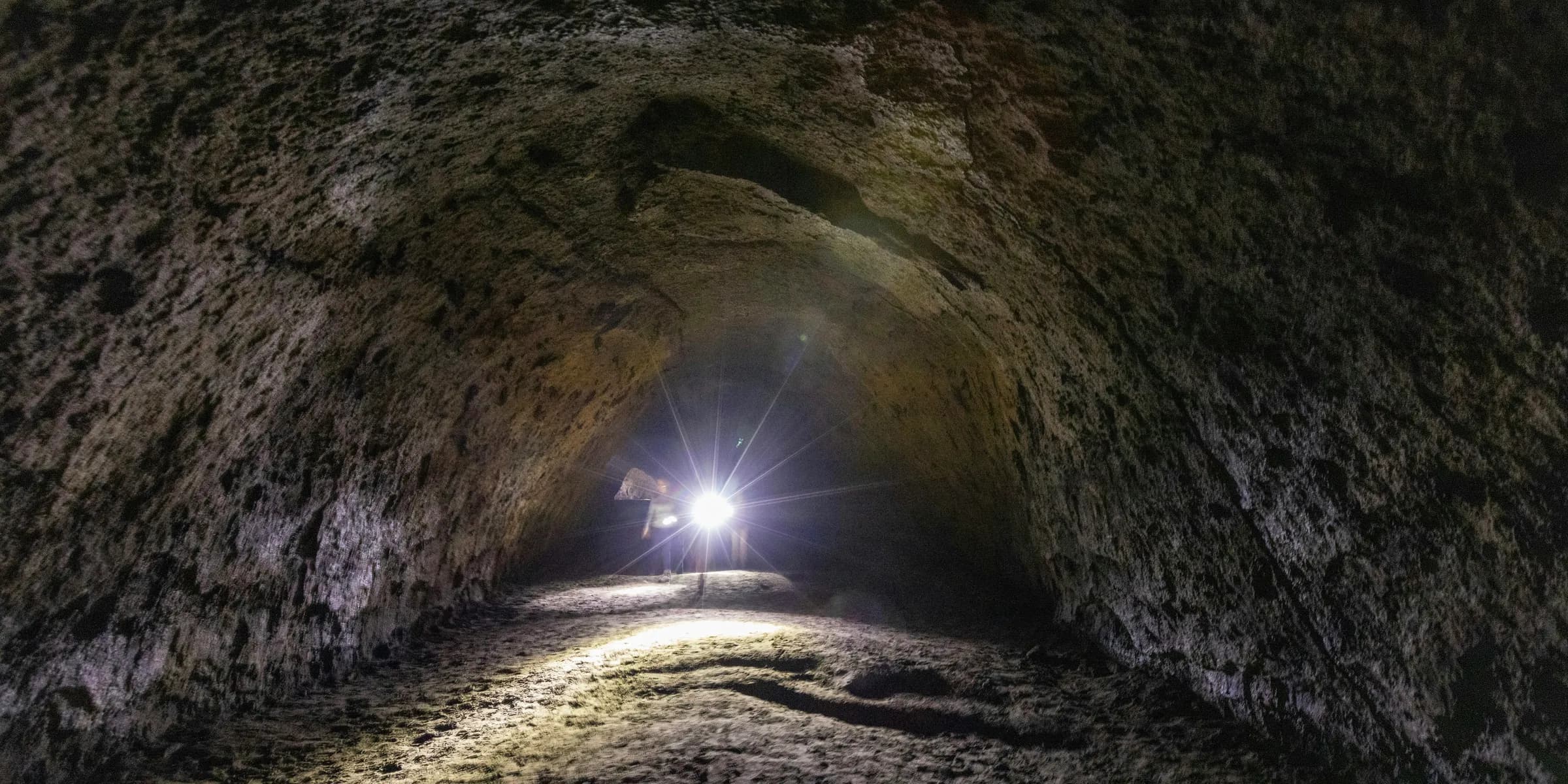 a man standing in a tunnel with a flashlight
