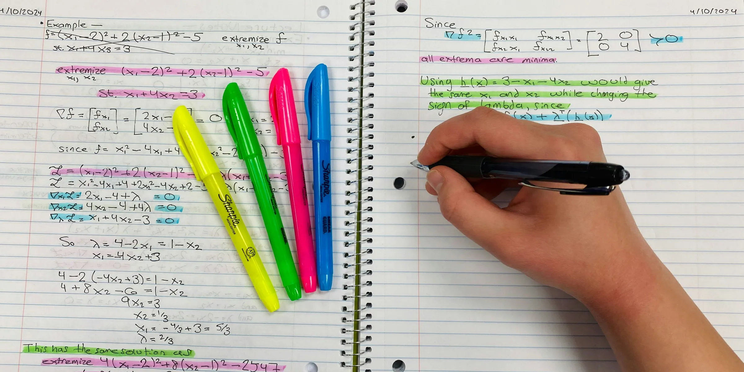 a person writing on a notebook with colored pens