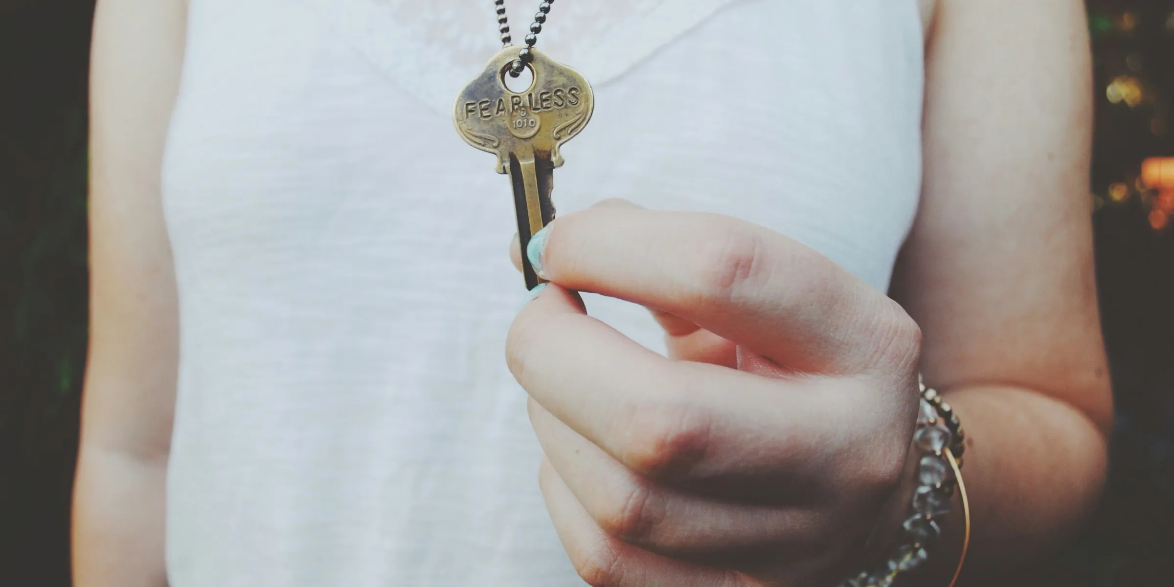 person holding gold-colored key pendant