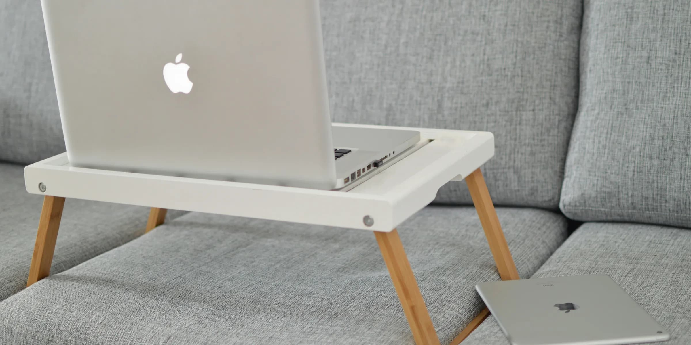 silver MacBook on laptop table on sofa