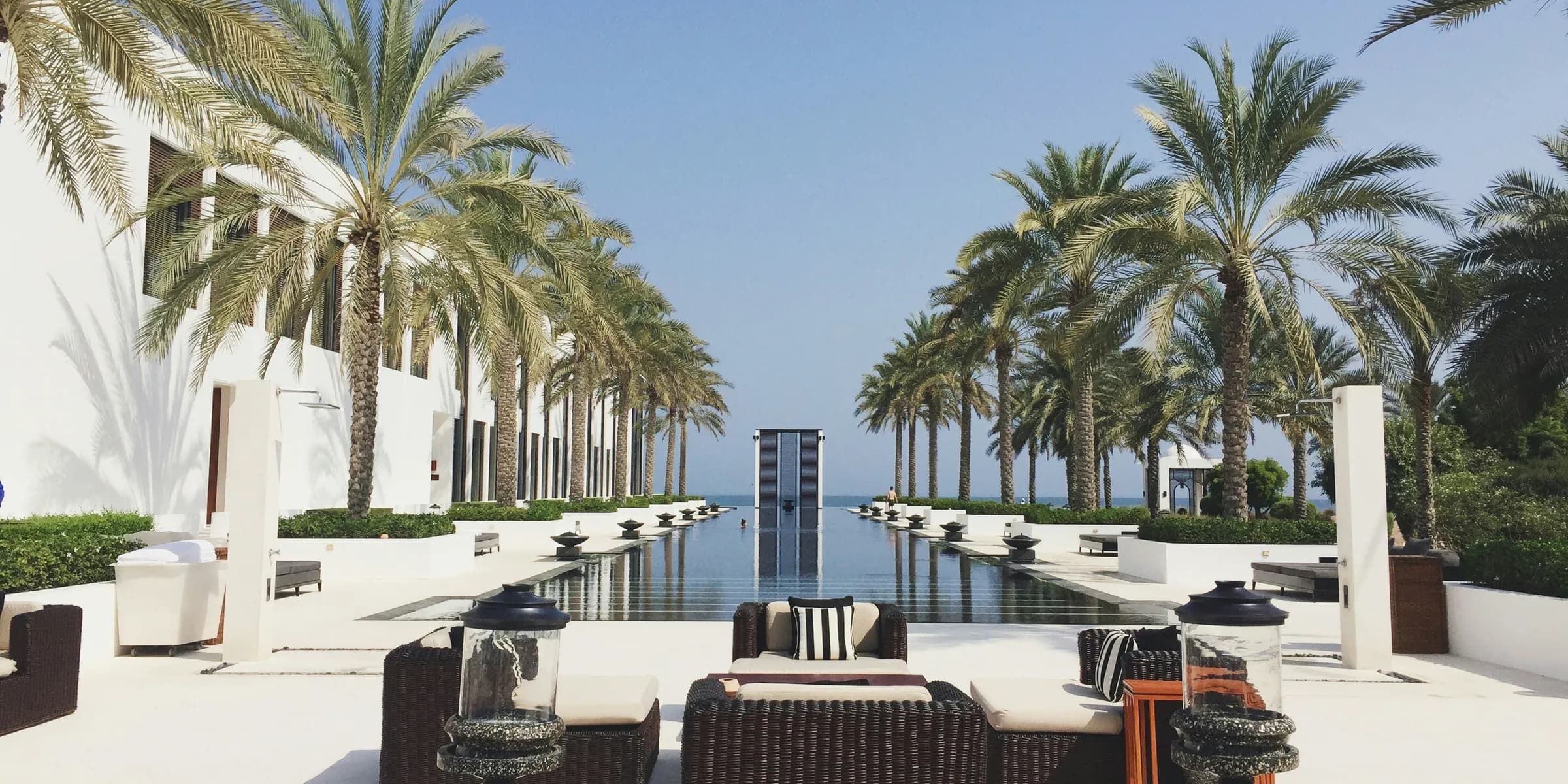 a pool with chairs and tables by it and palm trees