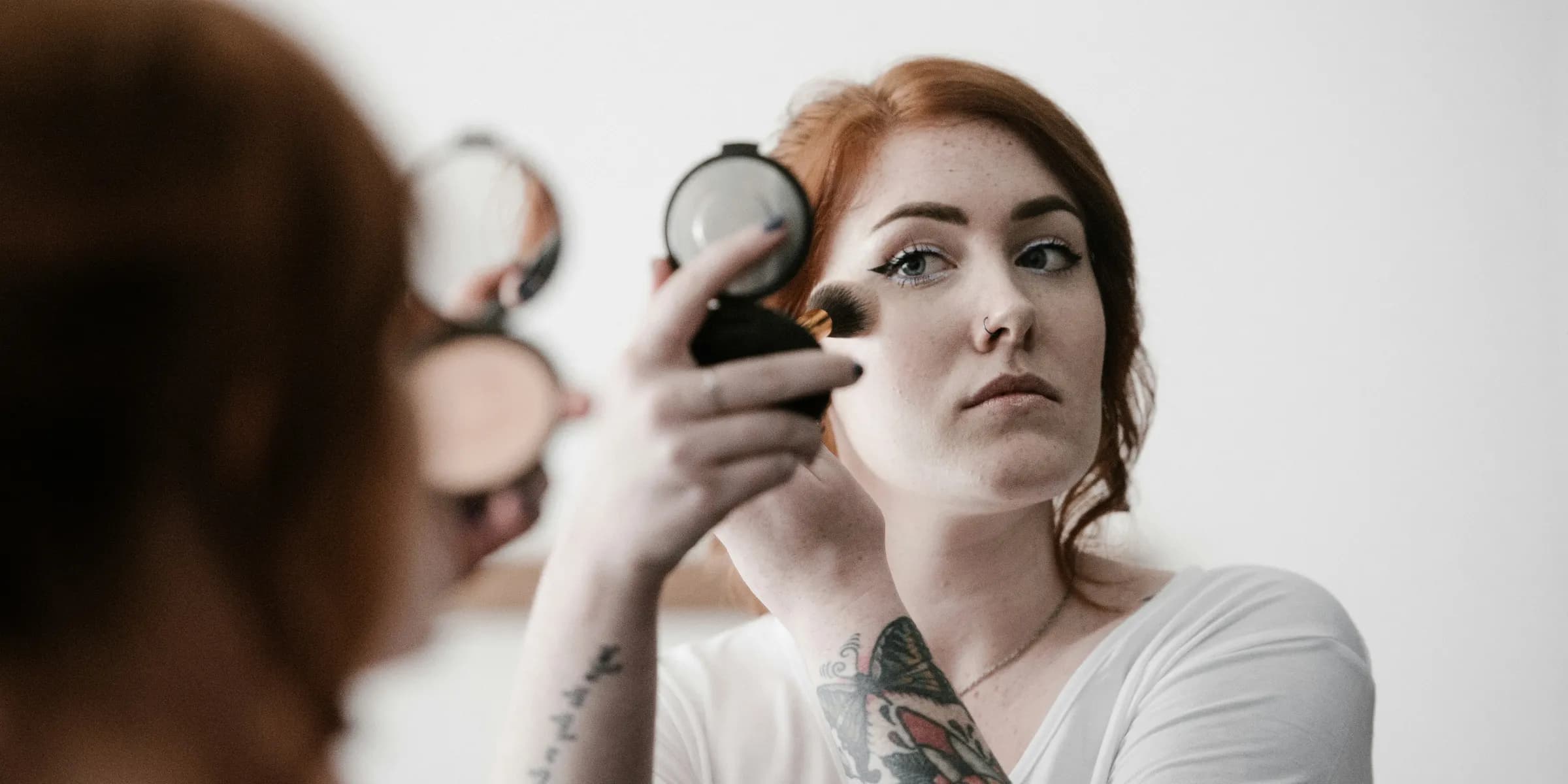 selective focus photography of woman applying blush-on on her face