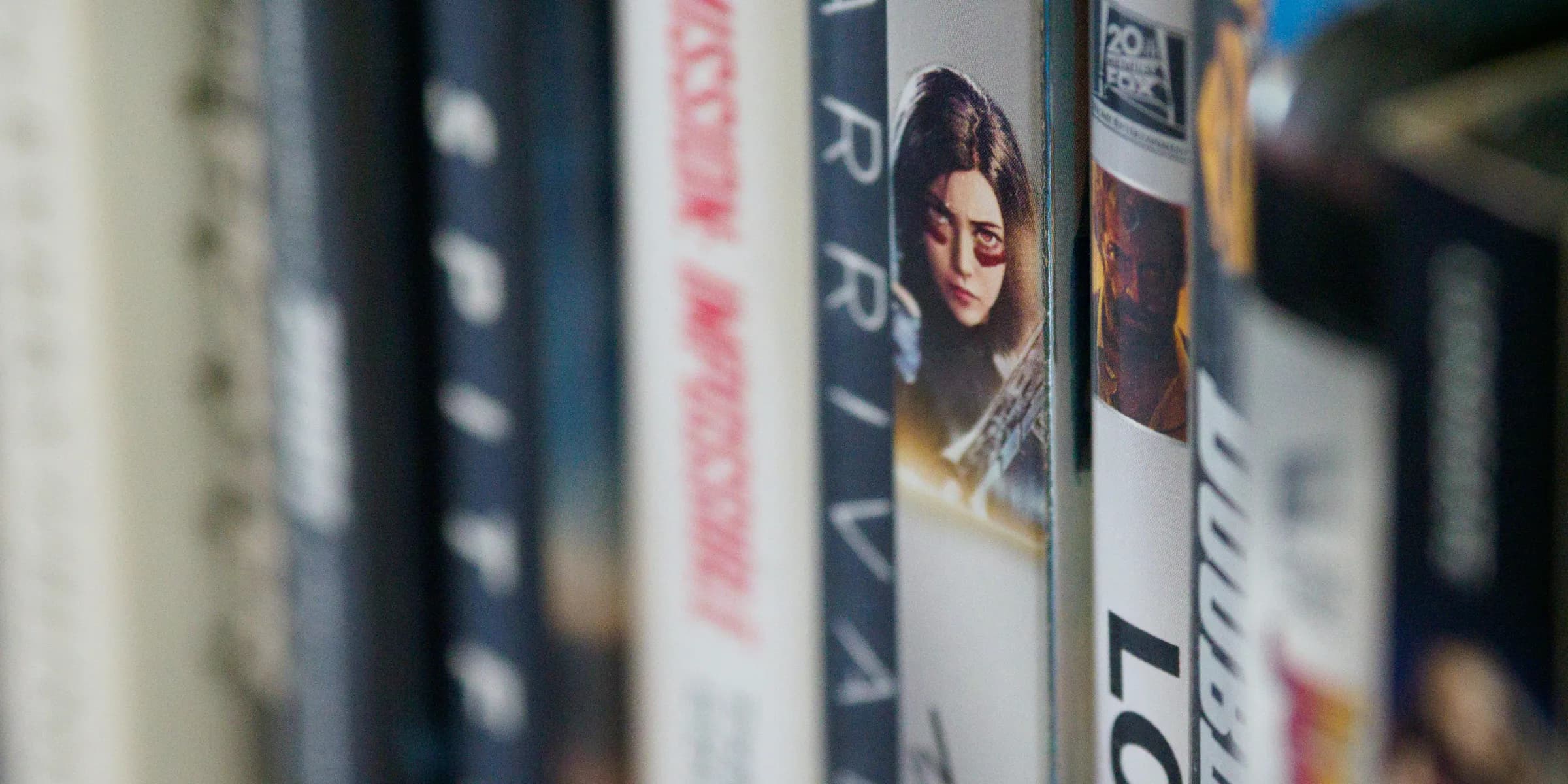 man in black suit jacket standing in front of books