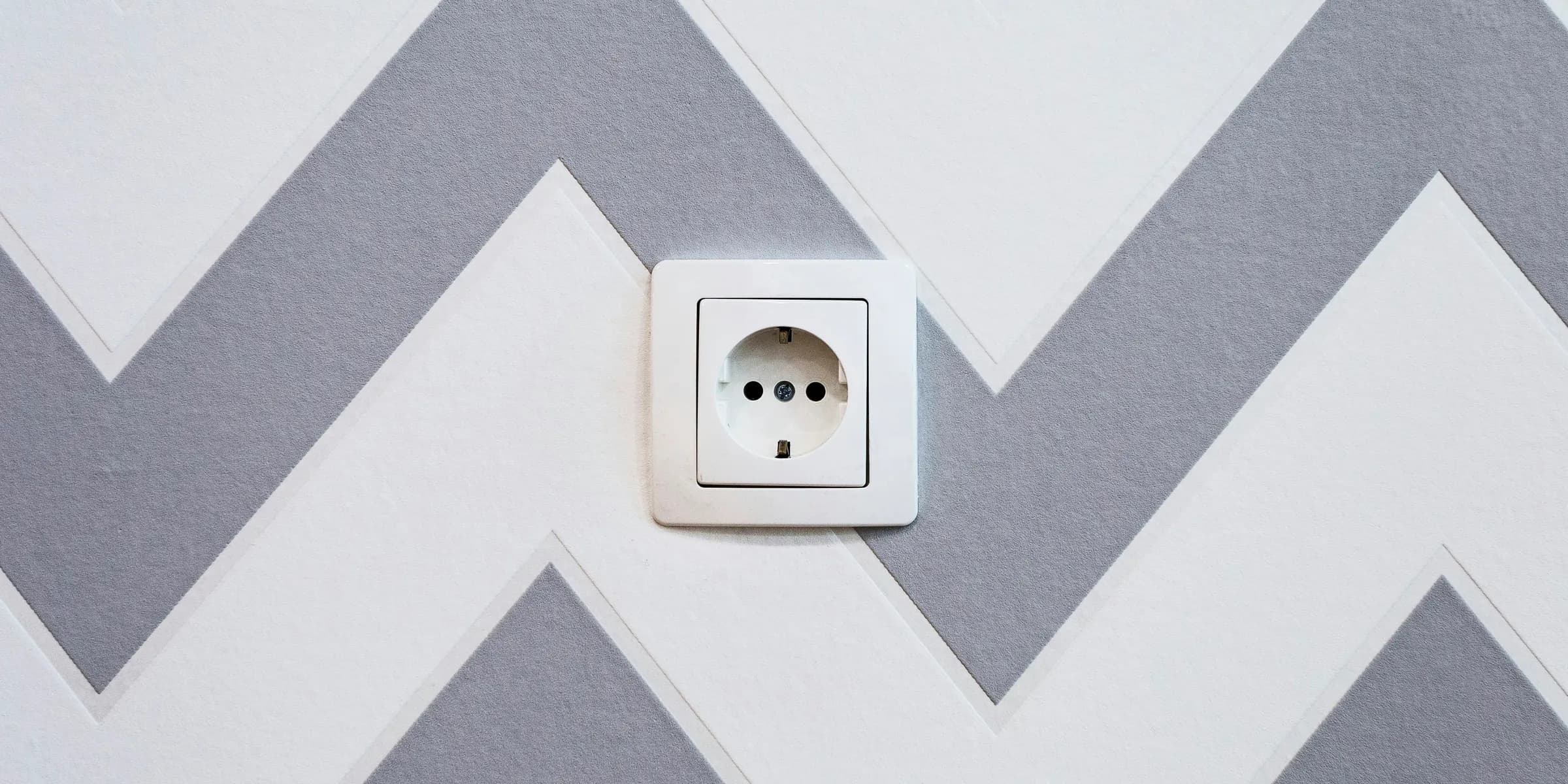 white power strip mounted on white and grey chevron painted wall