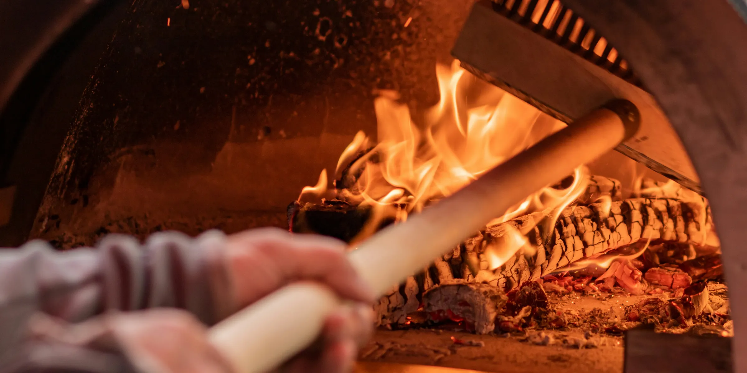 a close up of a person cooking food in a brick oven