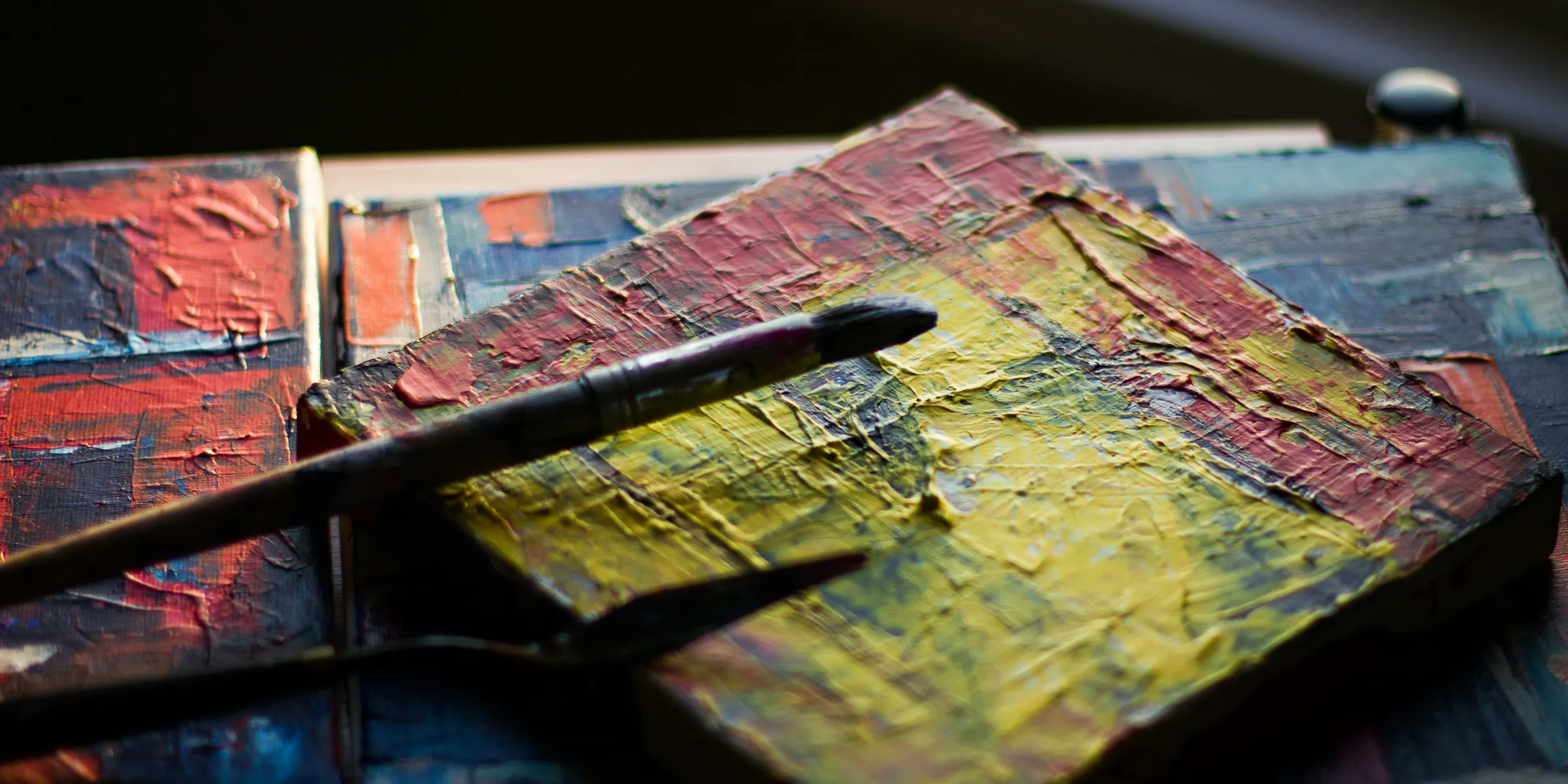 paintbrush resting on square multicolored painted block
