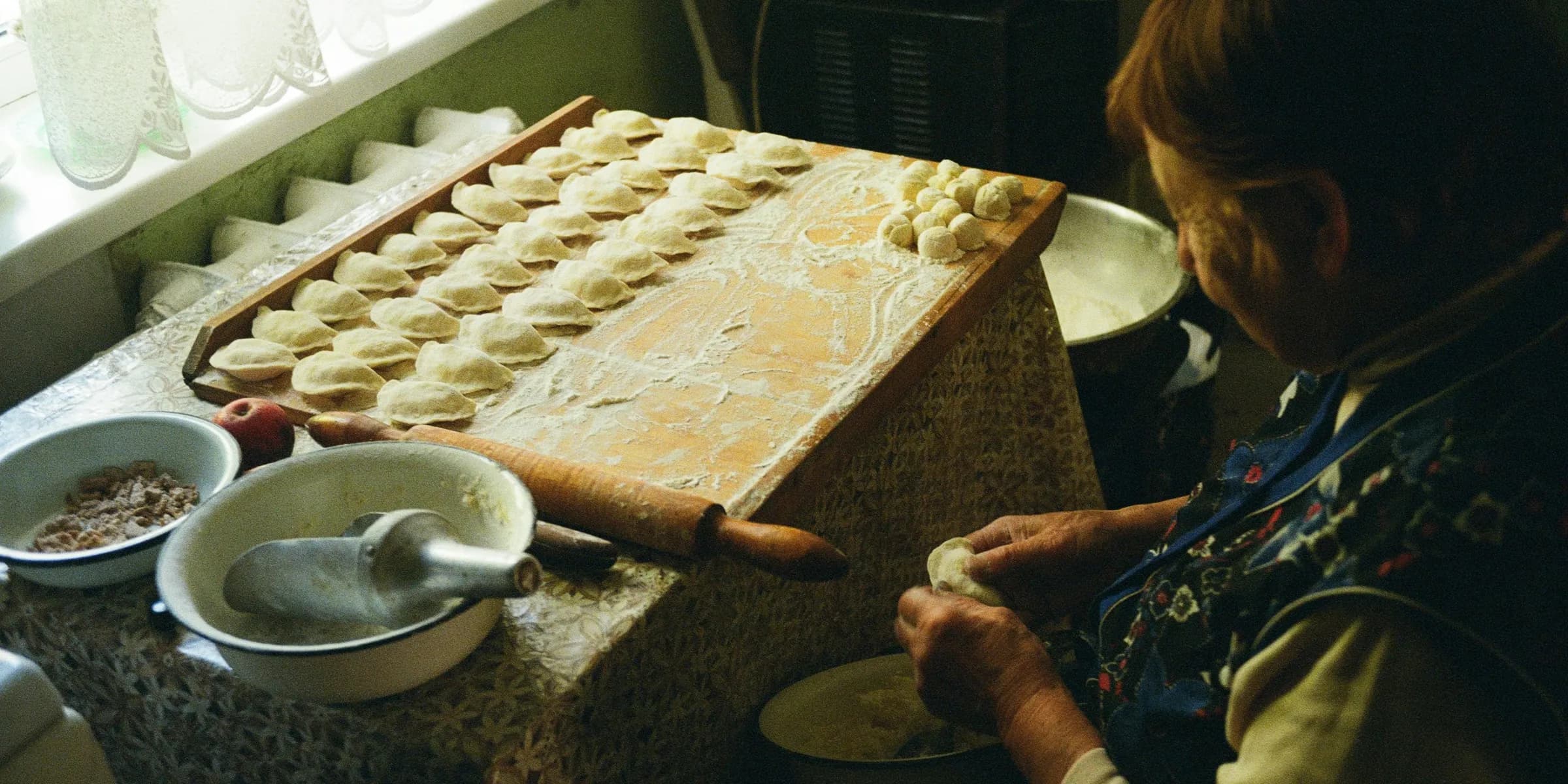 a woman in a kitchen making dough on a table