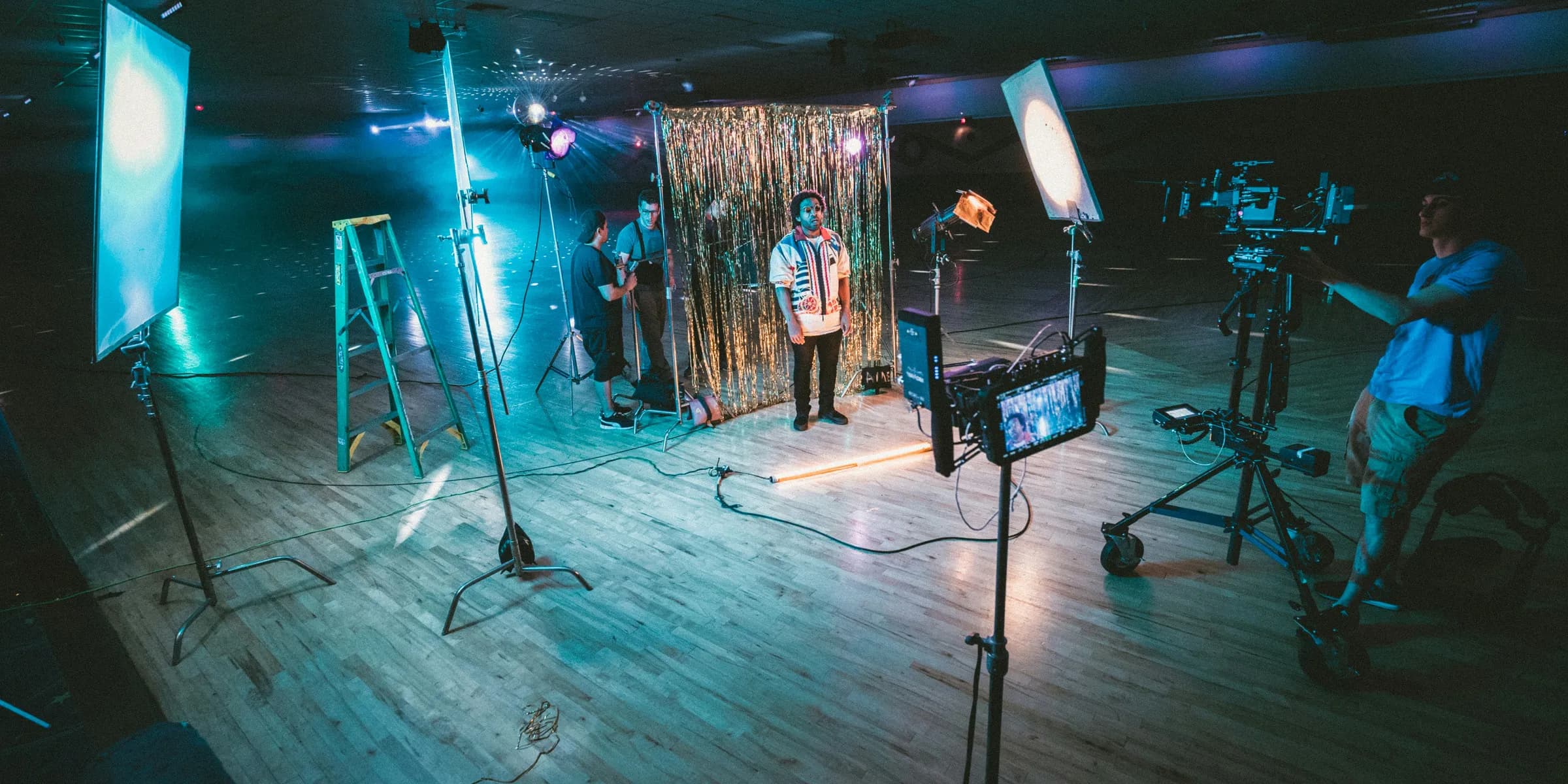 man standing in front of cameras with string lights background