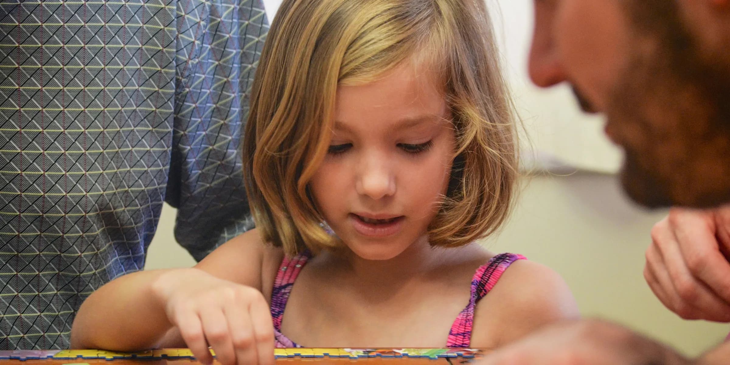 girl in blue and white polka dot tank top playing on brown wooden table