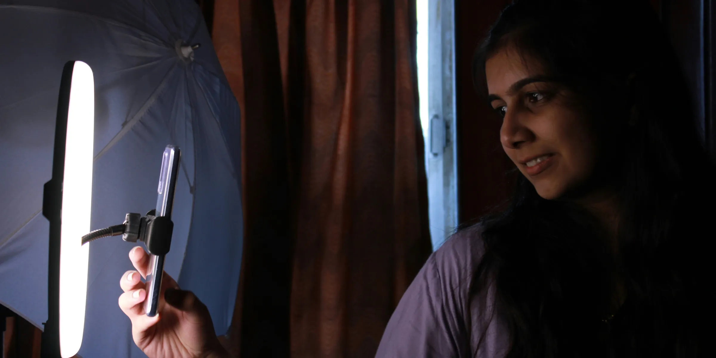 A woman holding a cell phone in front of a light