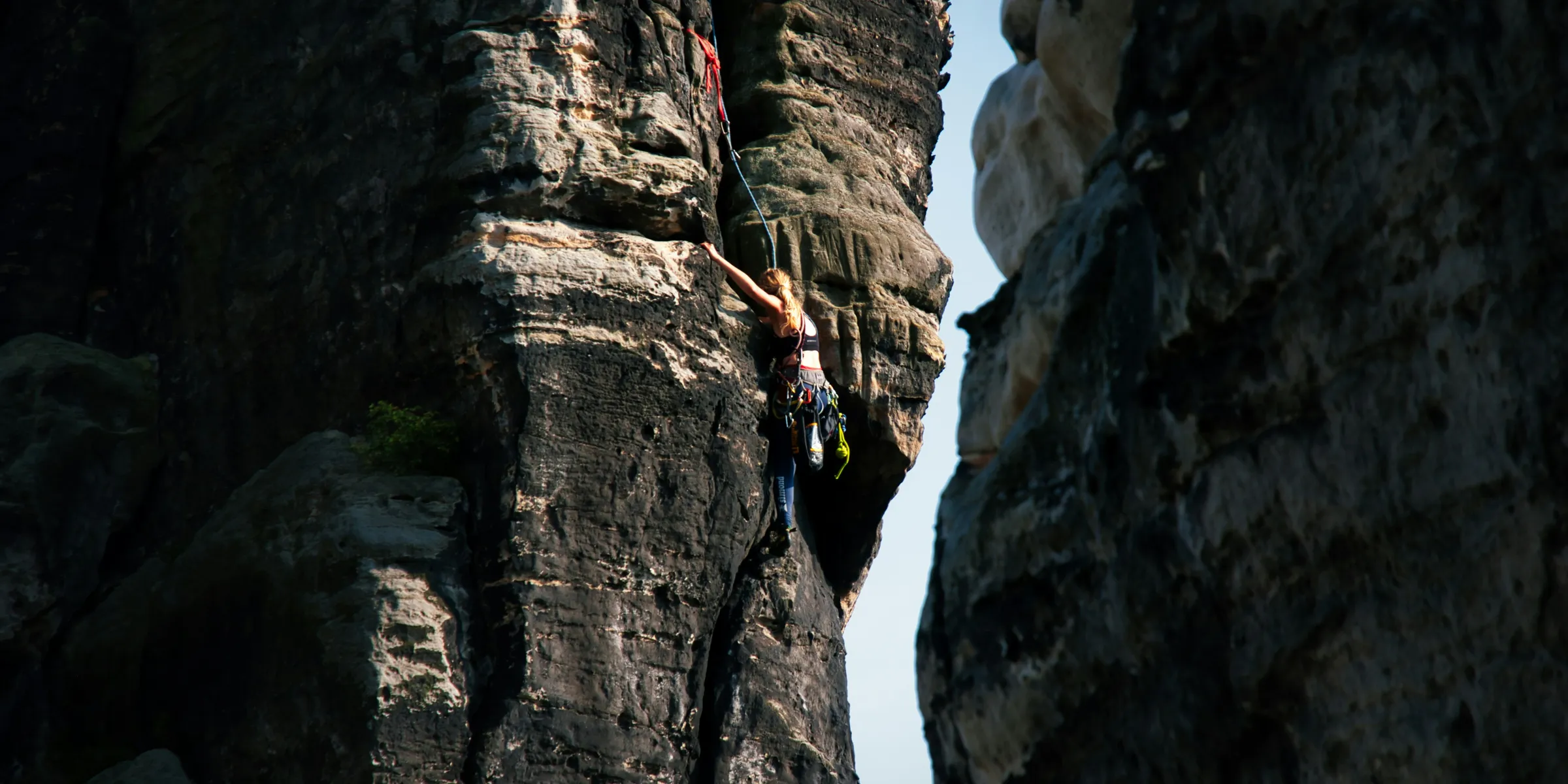 A rock climber ascends a steep cliff face.