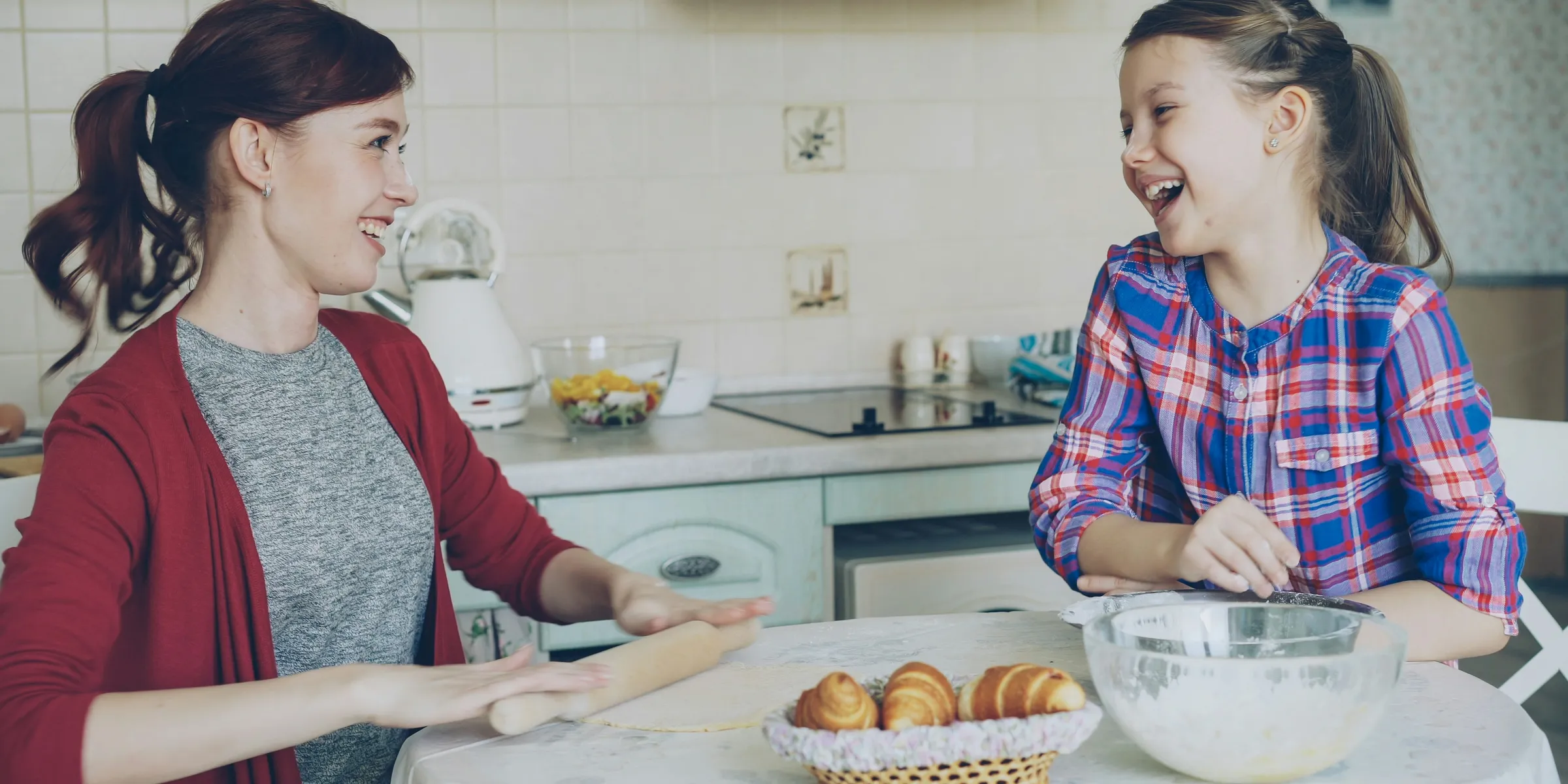 Mother and daughter happily bake together in the kitchen.