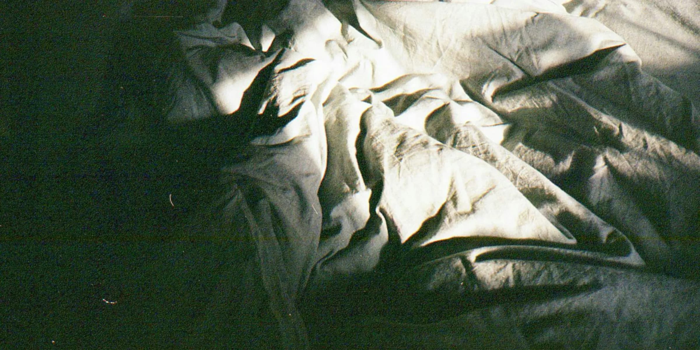 a person laying in a bed with a white sheet