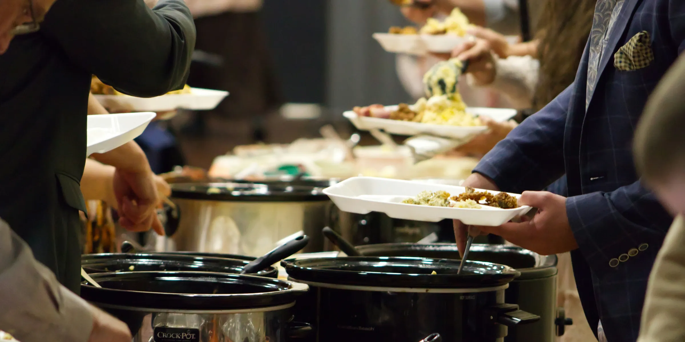 A group of people standing around a buffet line