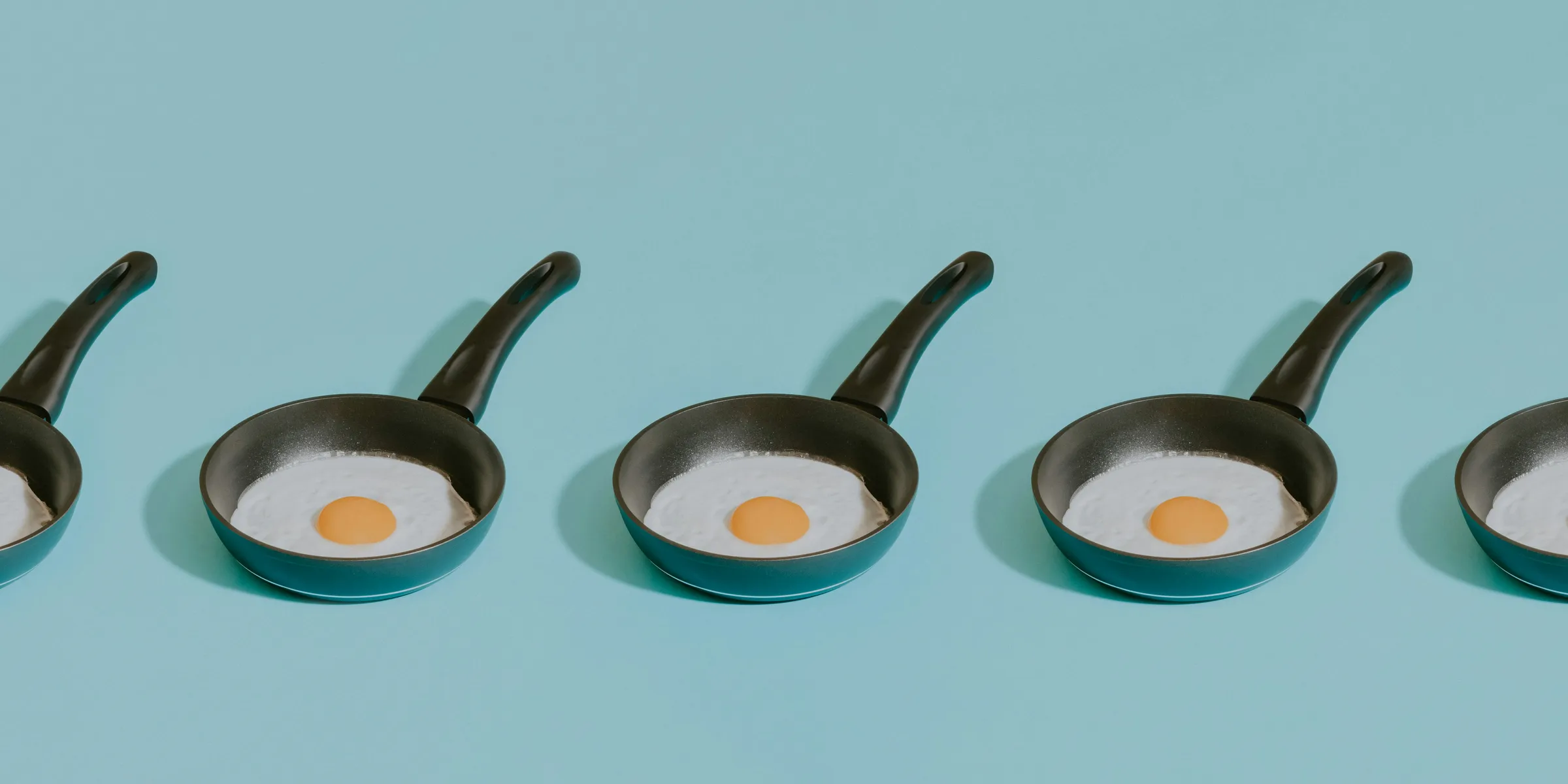 four frying pans with an egg in them