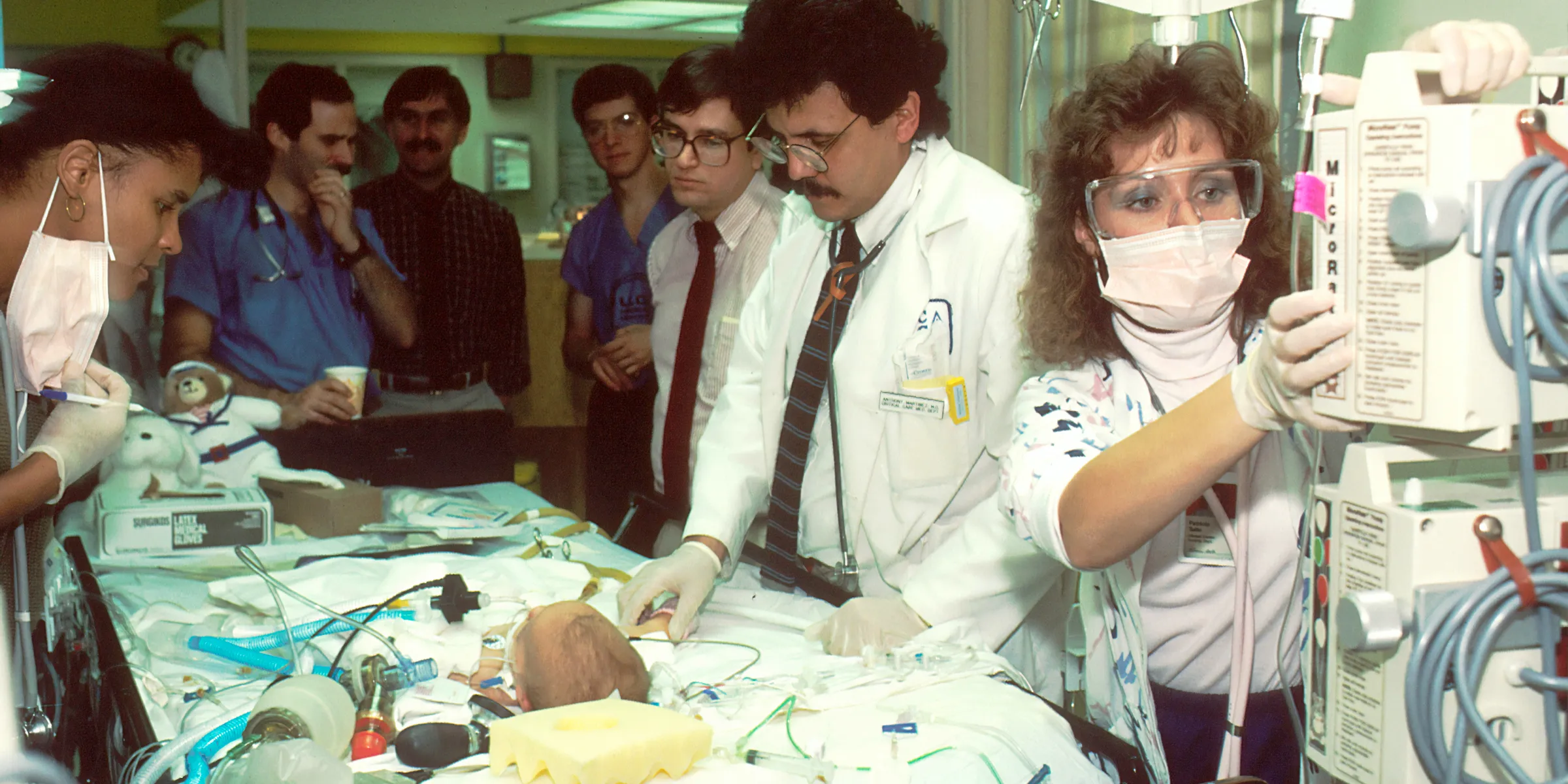 people beside baby lying on bed with medical apparatuses
