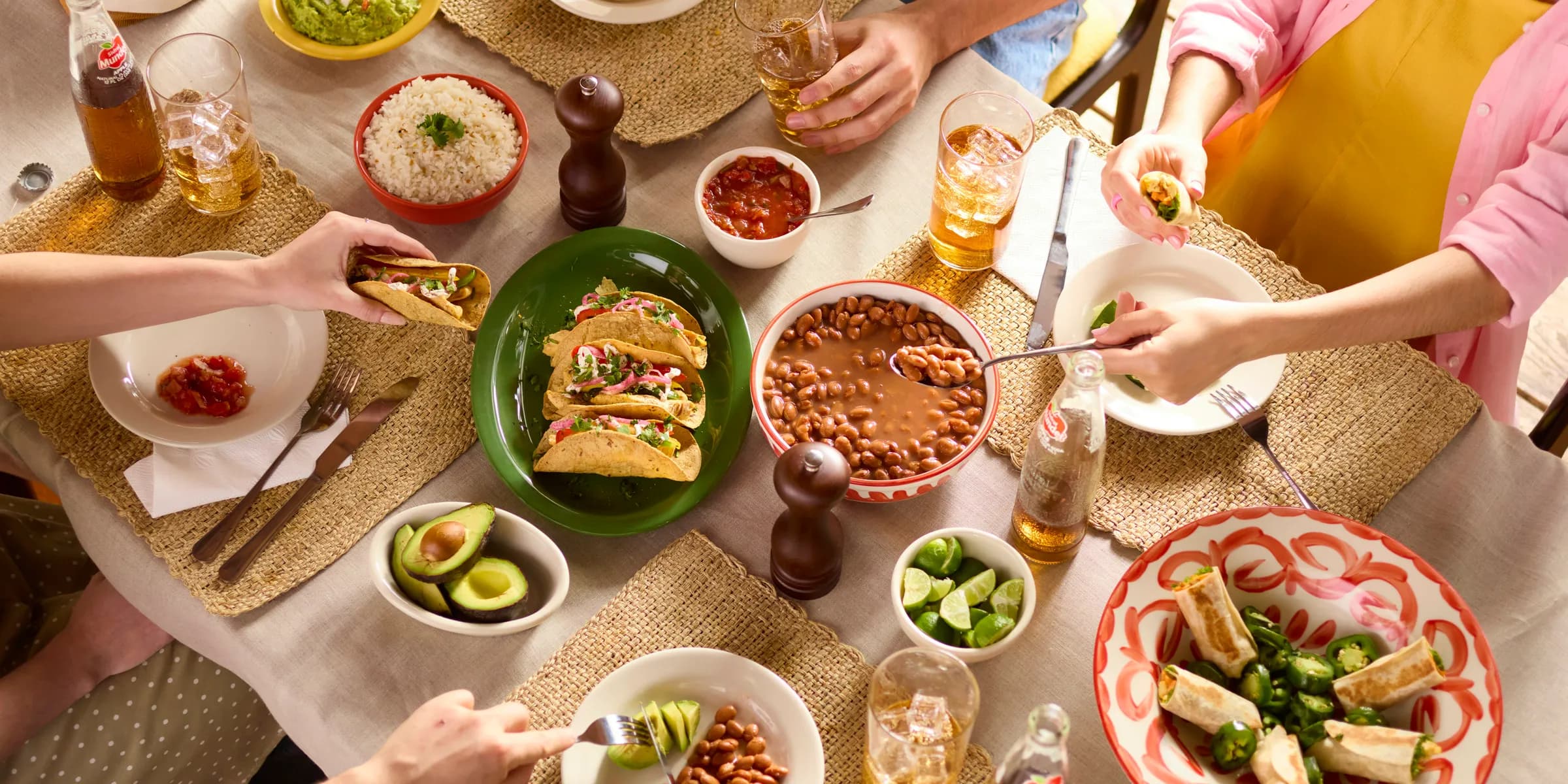 People are gathered around a table, enjoying a mexican feast.