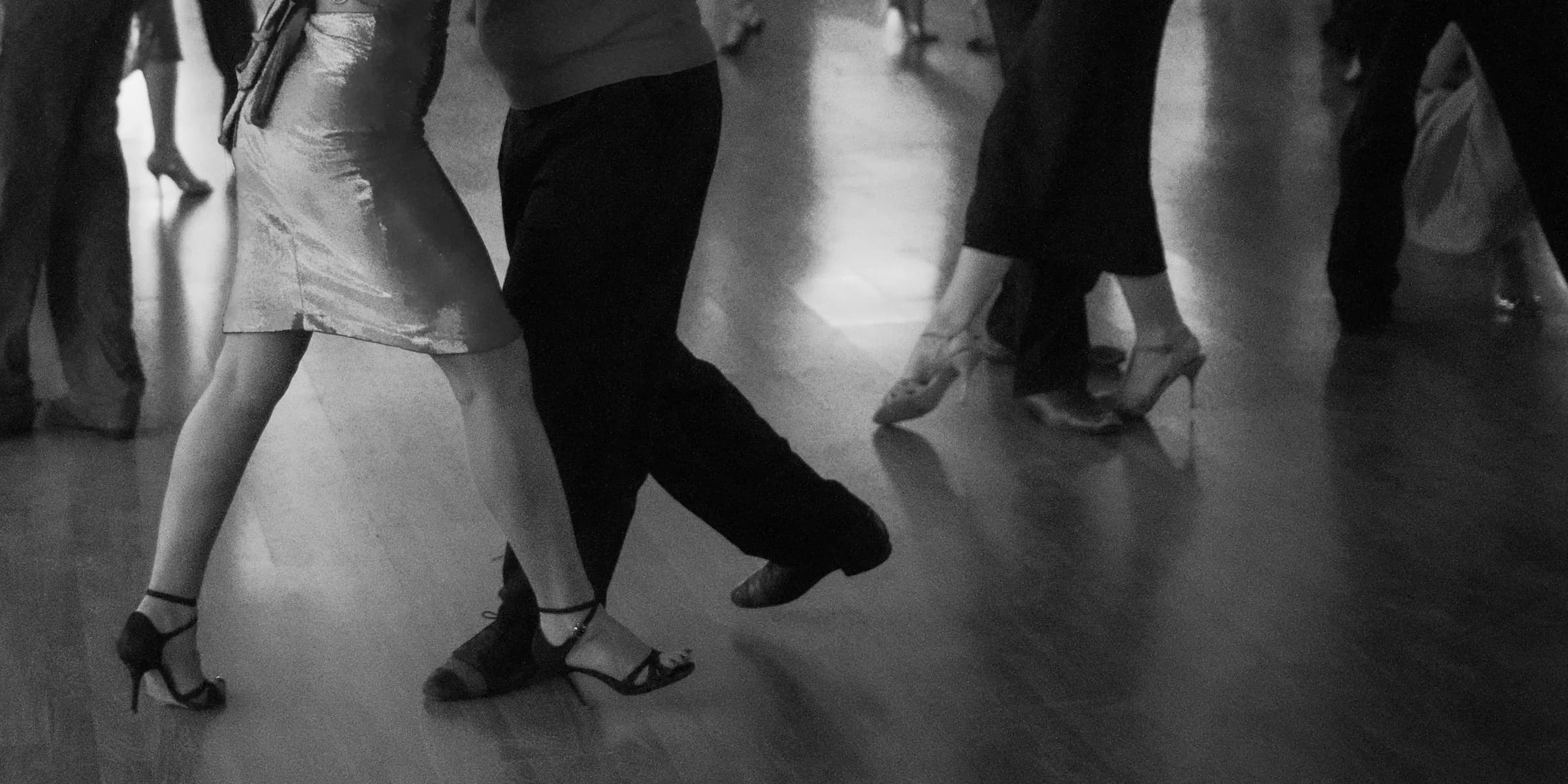 People are dancing on a wooden floor.