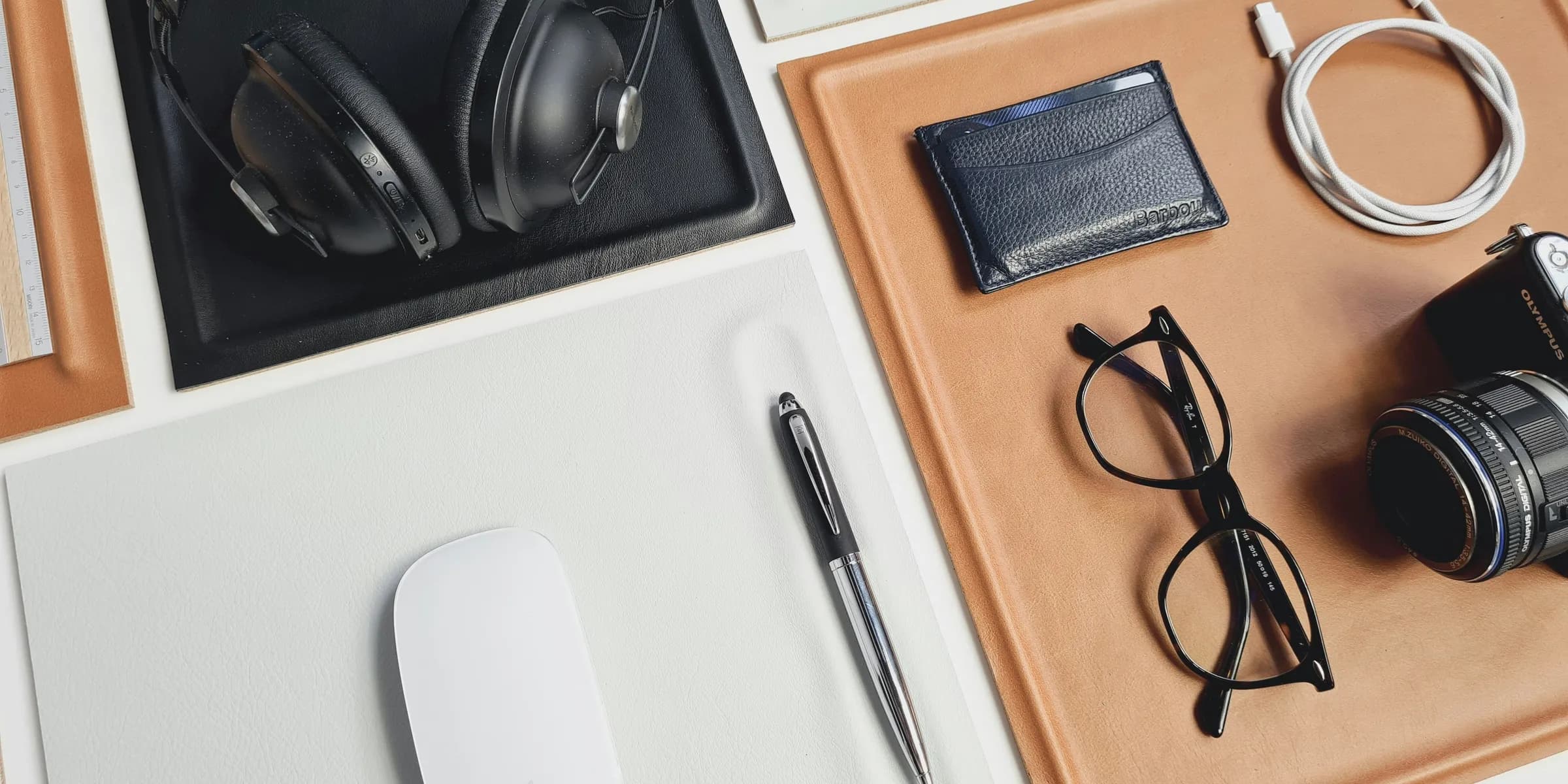 a desk with a camera, headphones, a wallet, a pen, and