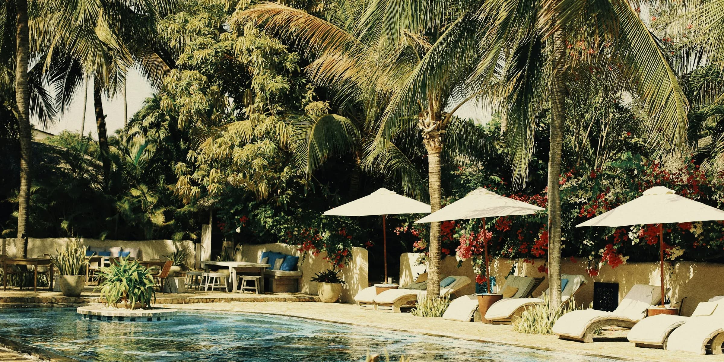 people sitting on white and brown outdoor lounge chairs near swimming pool during daytime