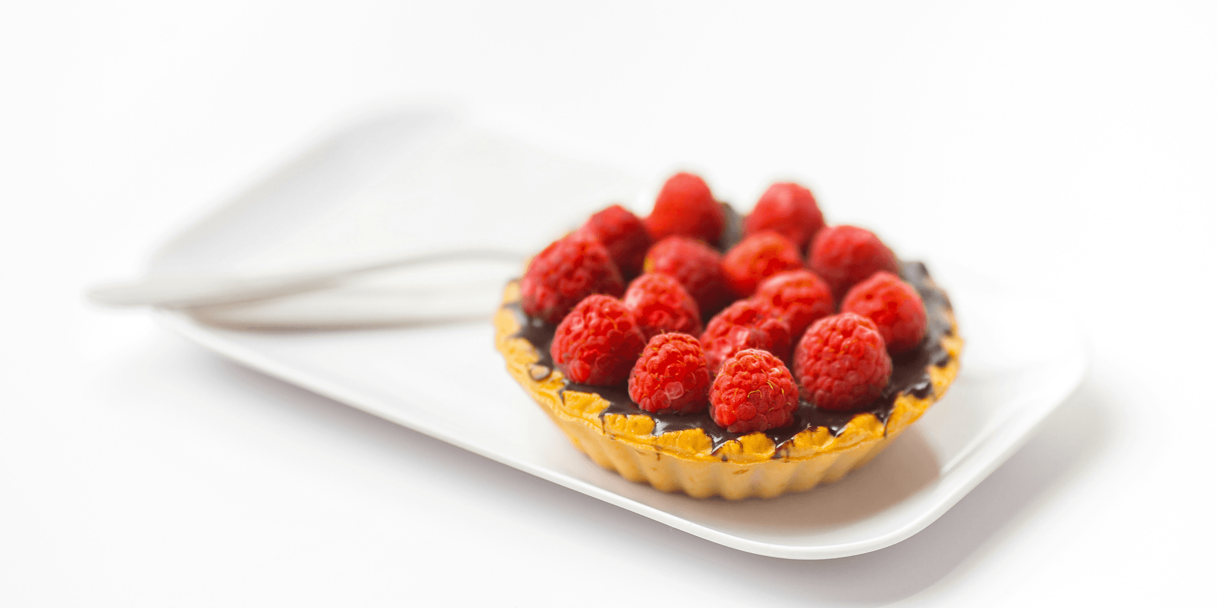 photo of chocolate cupcake with berry toppings on white ceramic plate