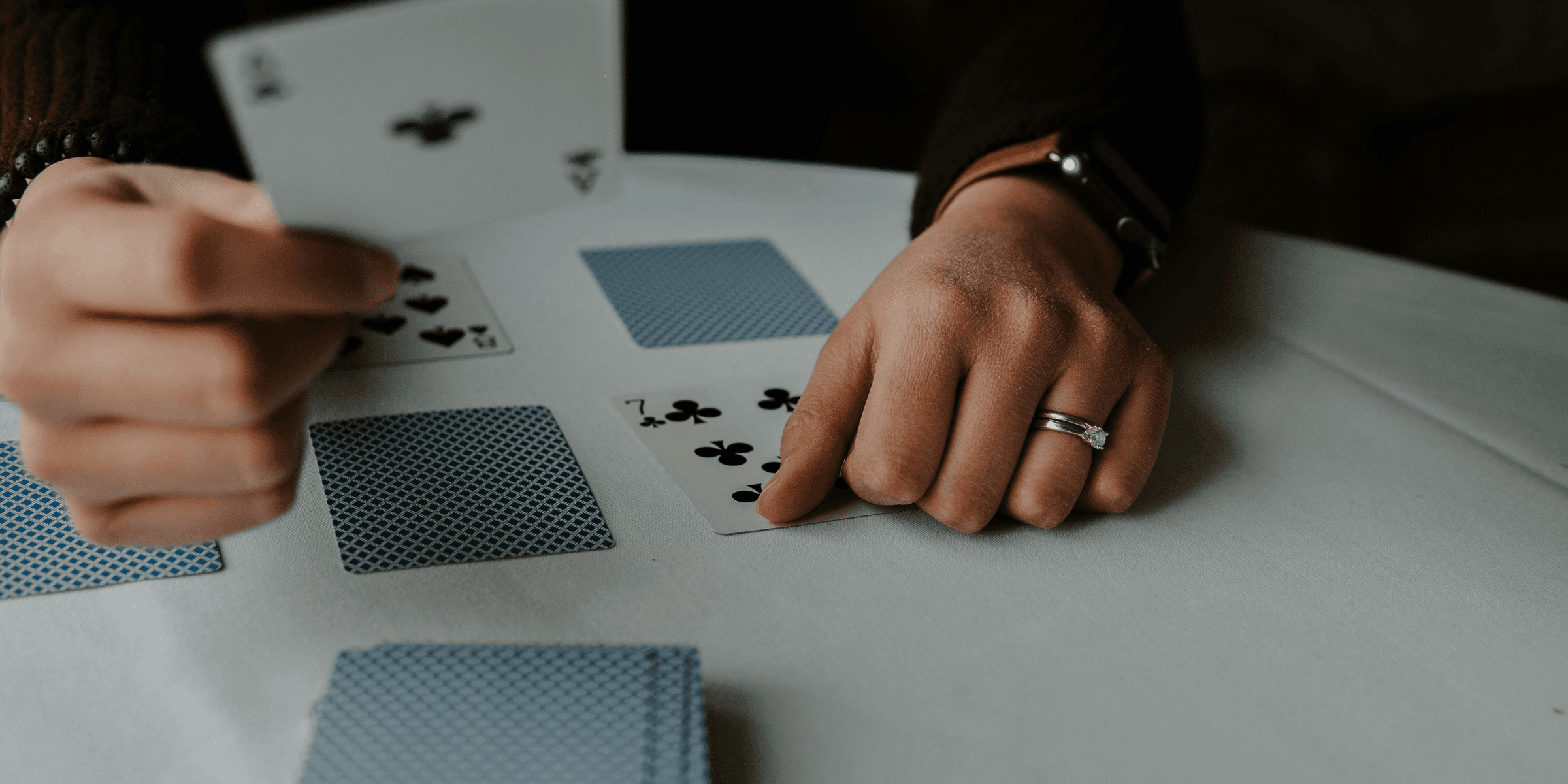 person holding playing cards on white table