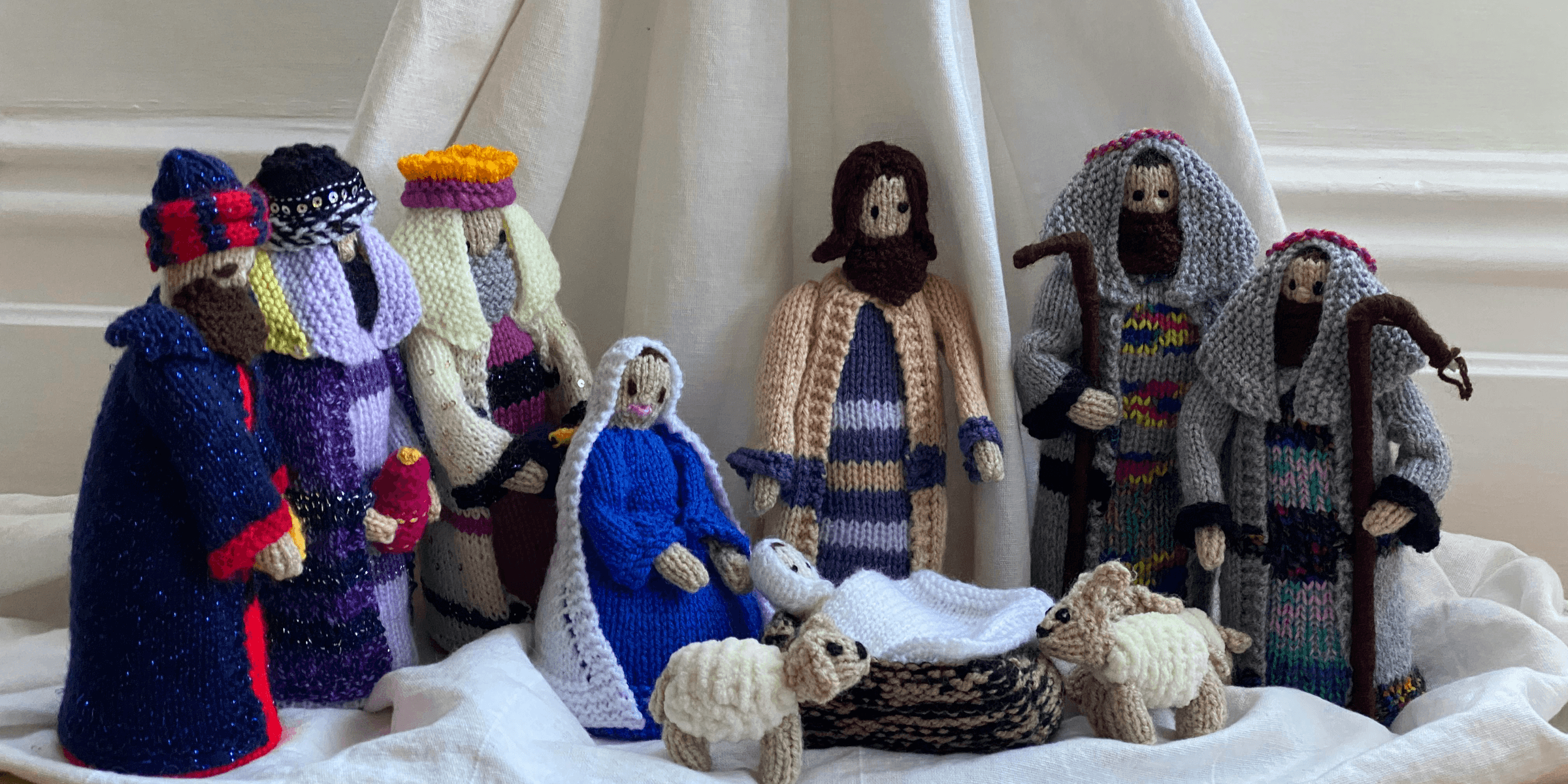 three white and blue knitted dolls on white textile