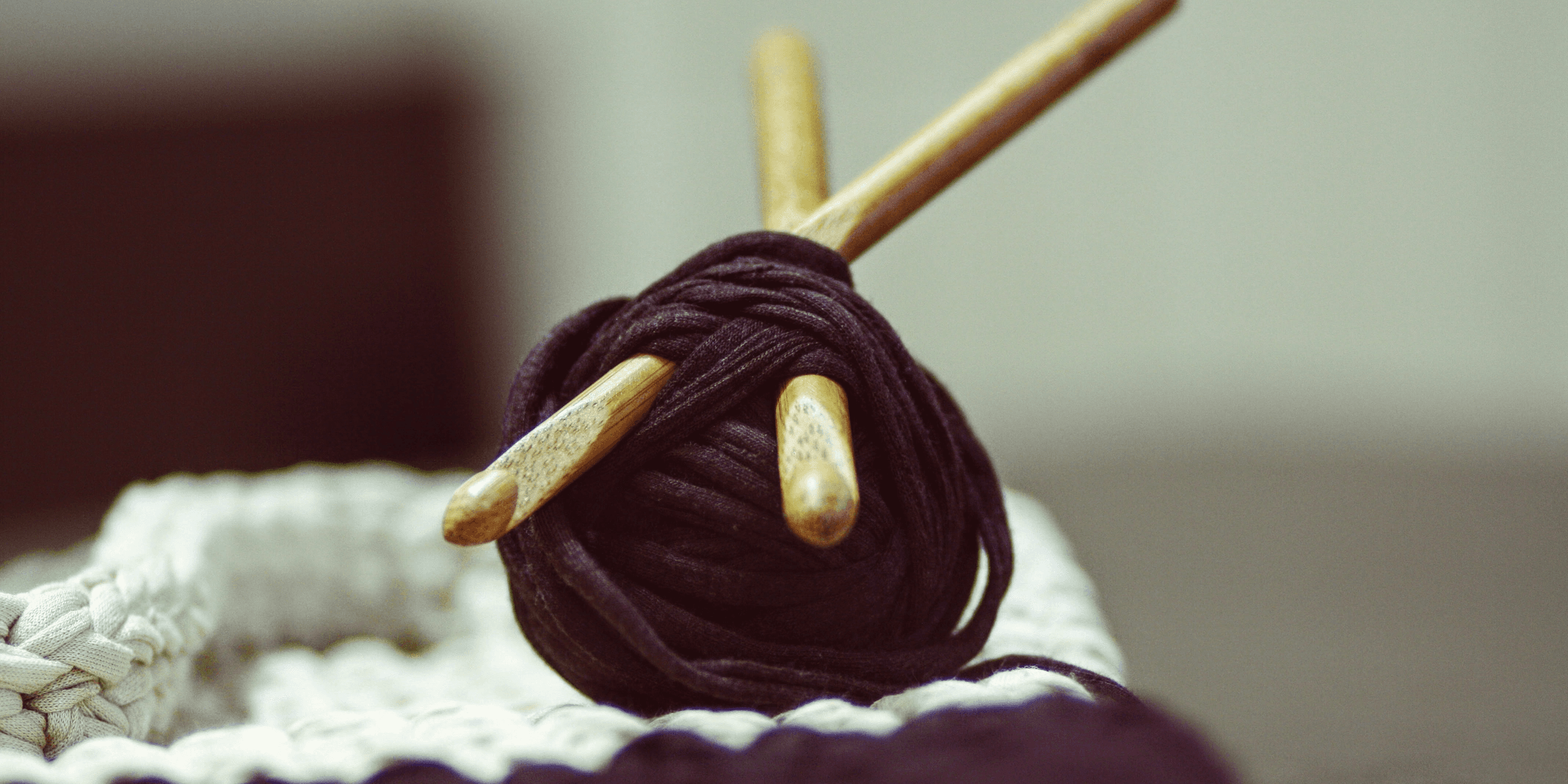 brown yarn roll with two brown crochet hooks on top of white surface