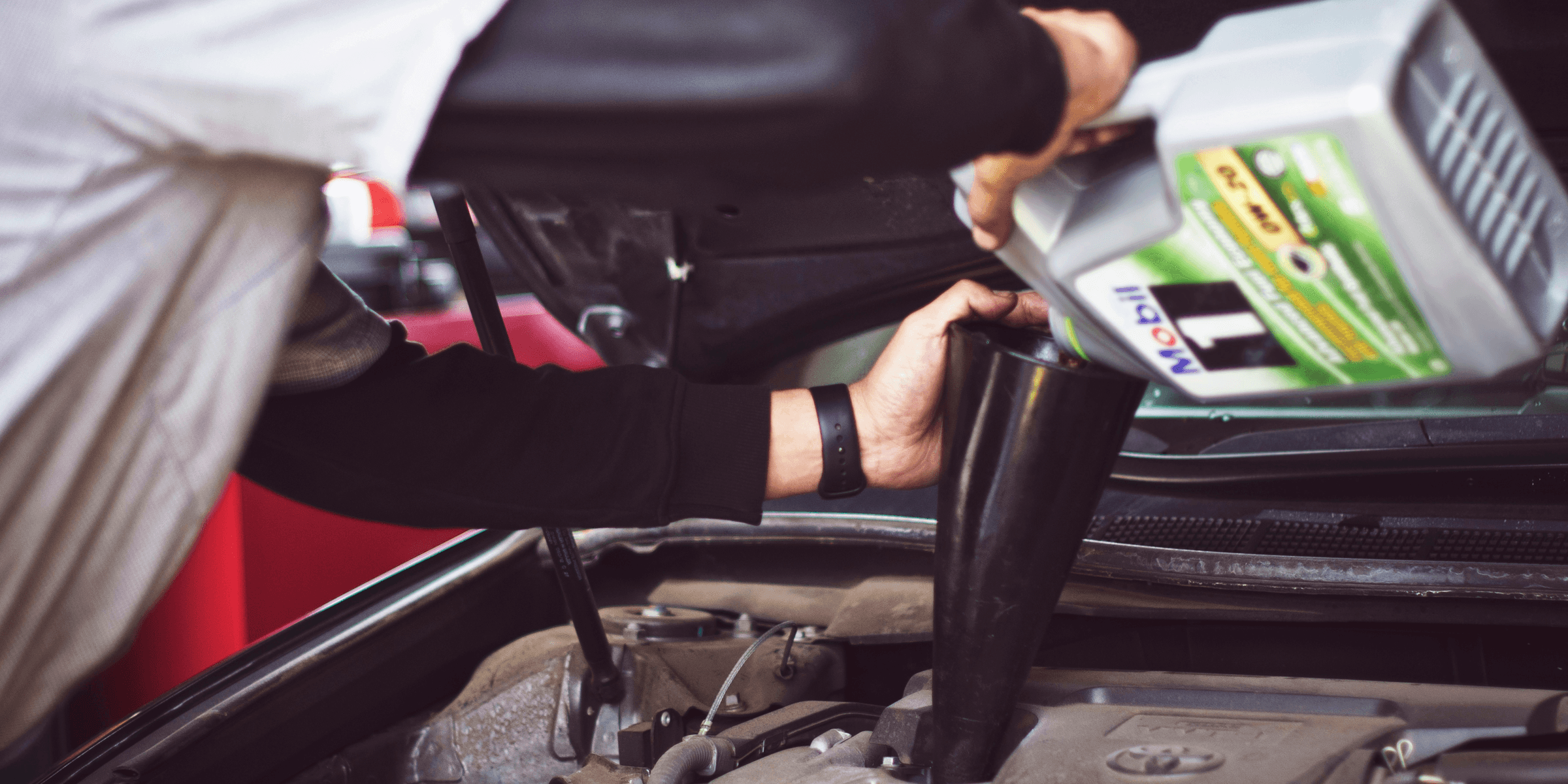 man refilling motor oil on car engine bay.