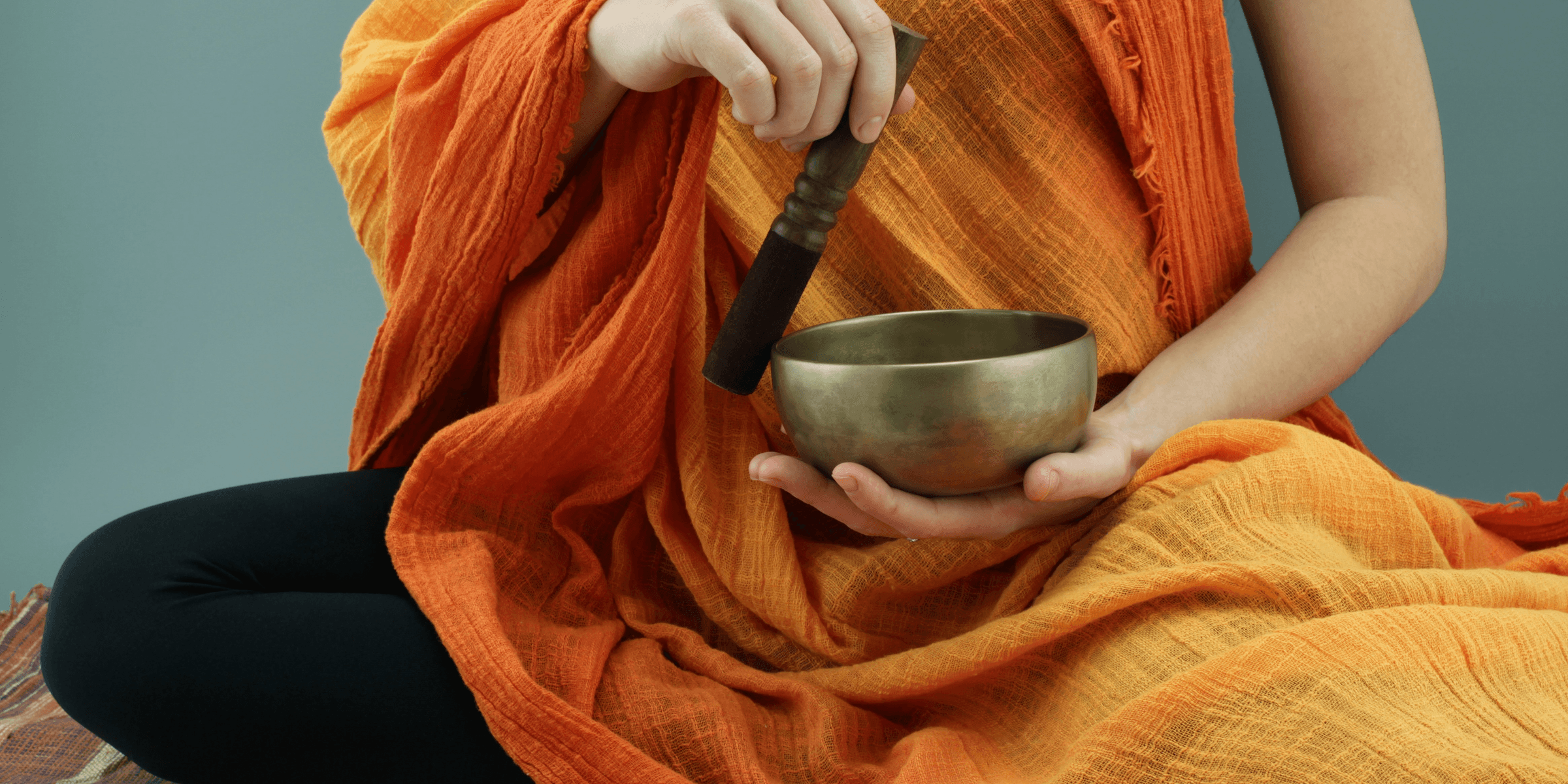 person in orange scarf holding silver round bowl.