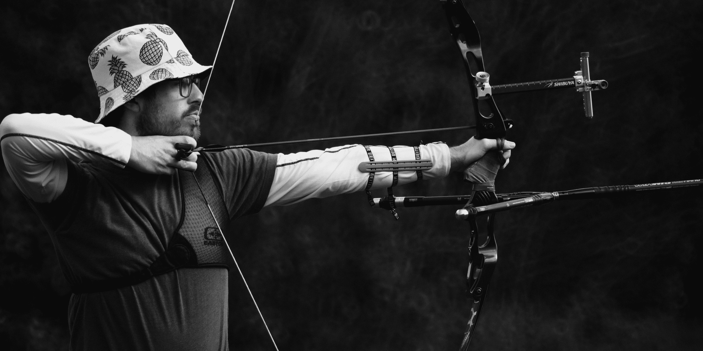 man in black shirt and brown pants holding bow.