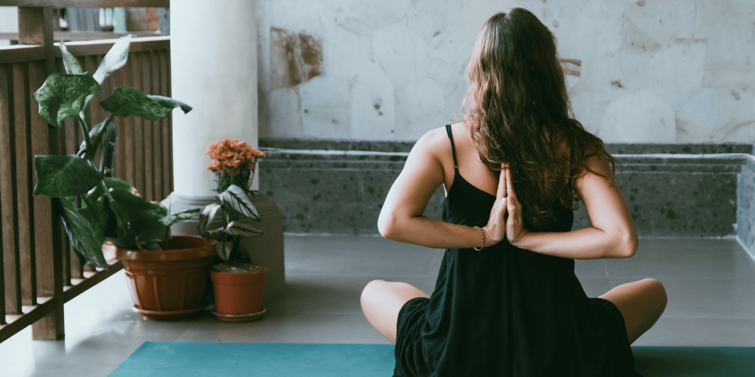 woman wearing black shirt sitting on green yoga mat.