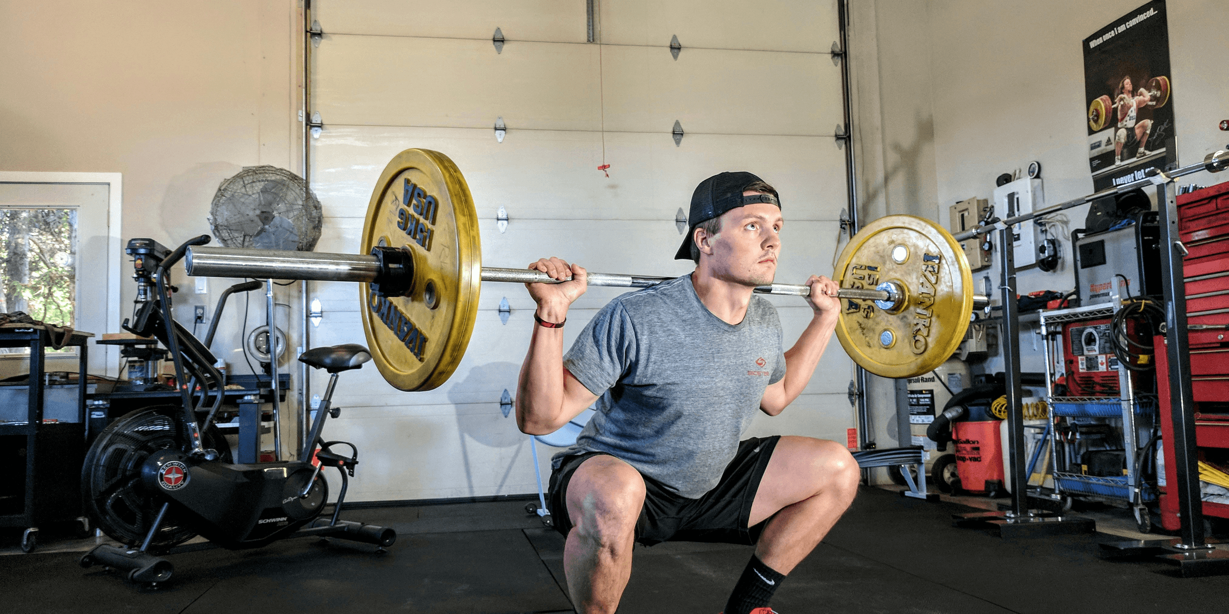 man lifting barbell on back inside gym.