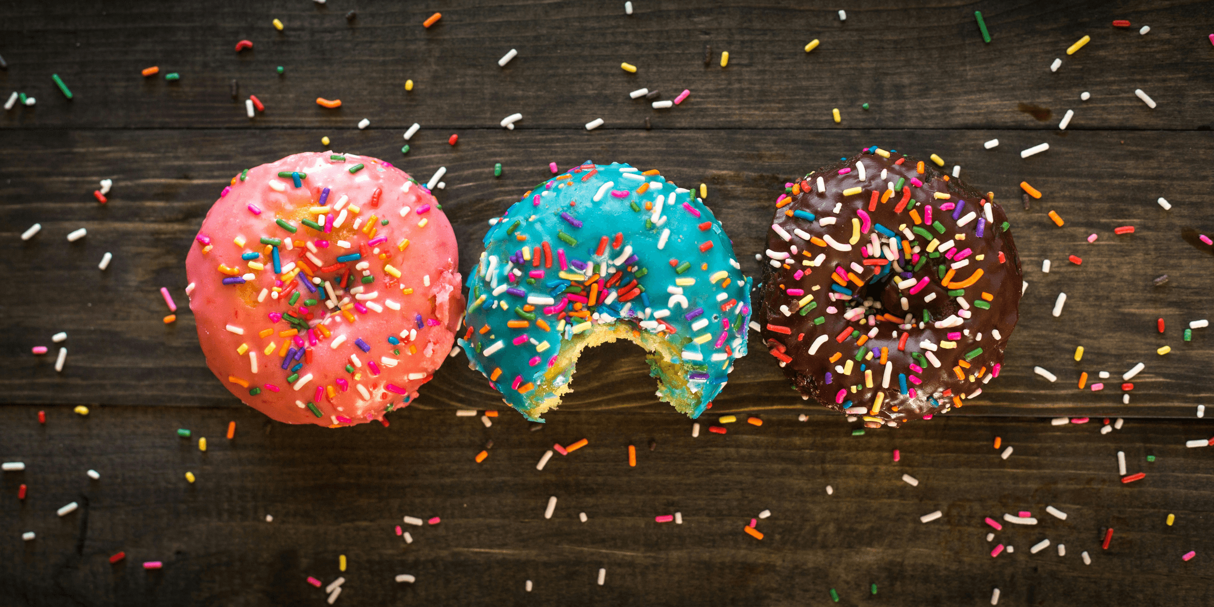 pink, blue, and chocolate with sprinkles doughnuts on table
