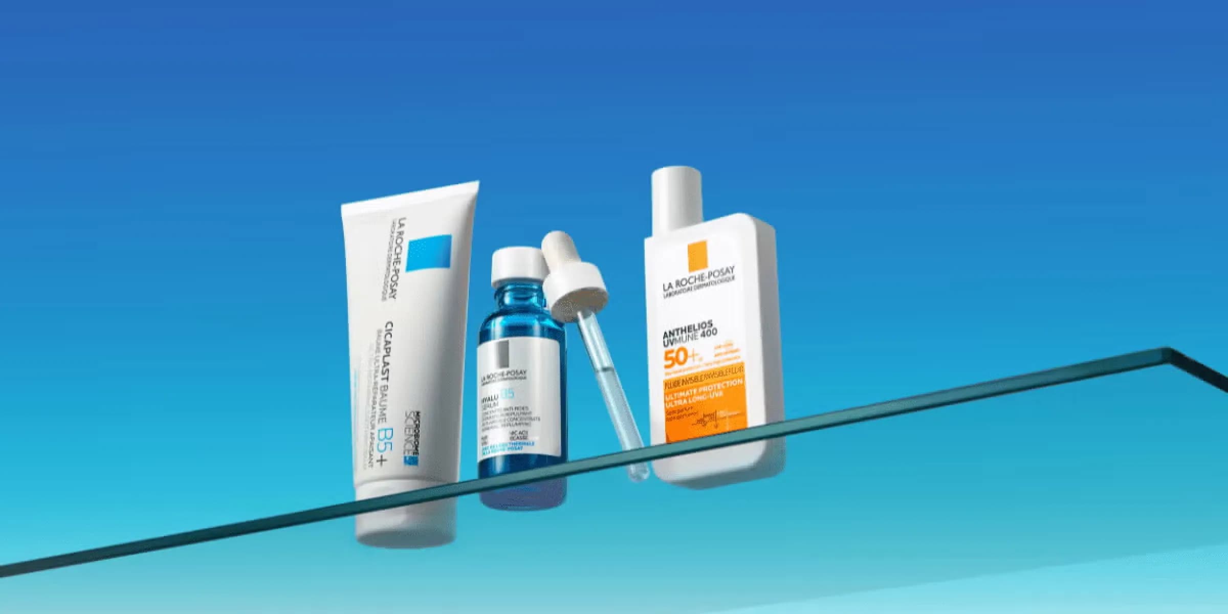 assorted skincare products on a glass surface with a blue background