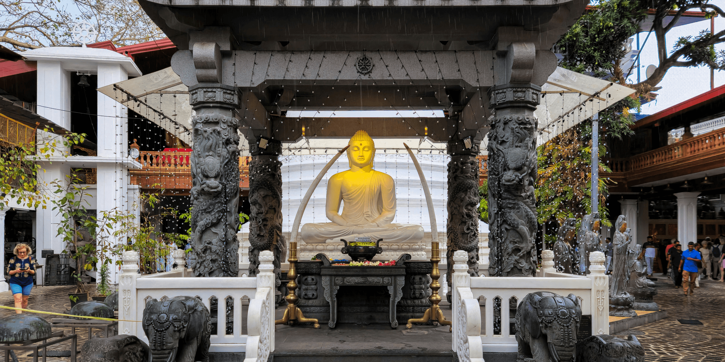 A golden buddha statue sits inside a pavilion..