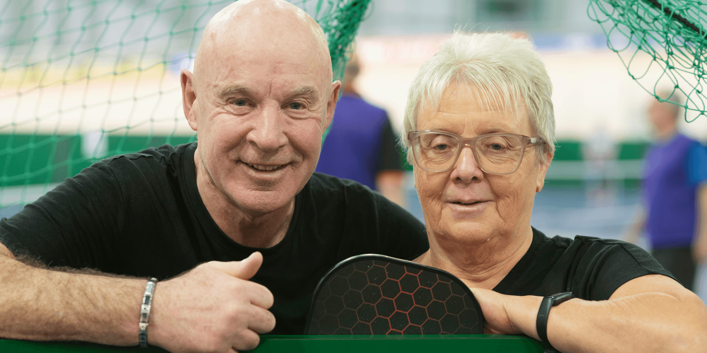 Smiling couple in front of a net..