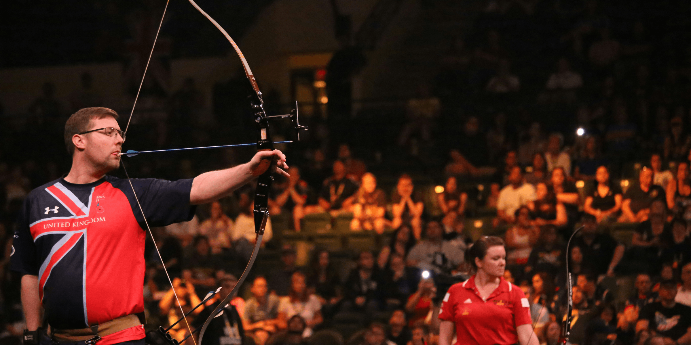 man doing archery near woman holding bow.