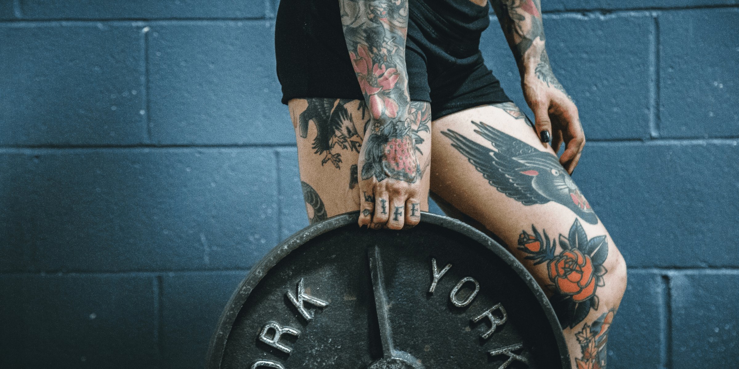 person carrying black weight plate with right hand.