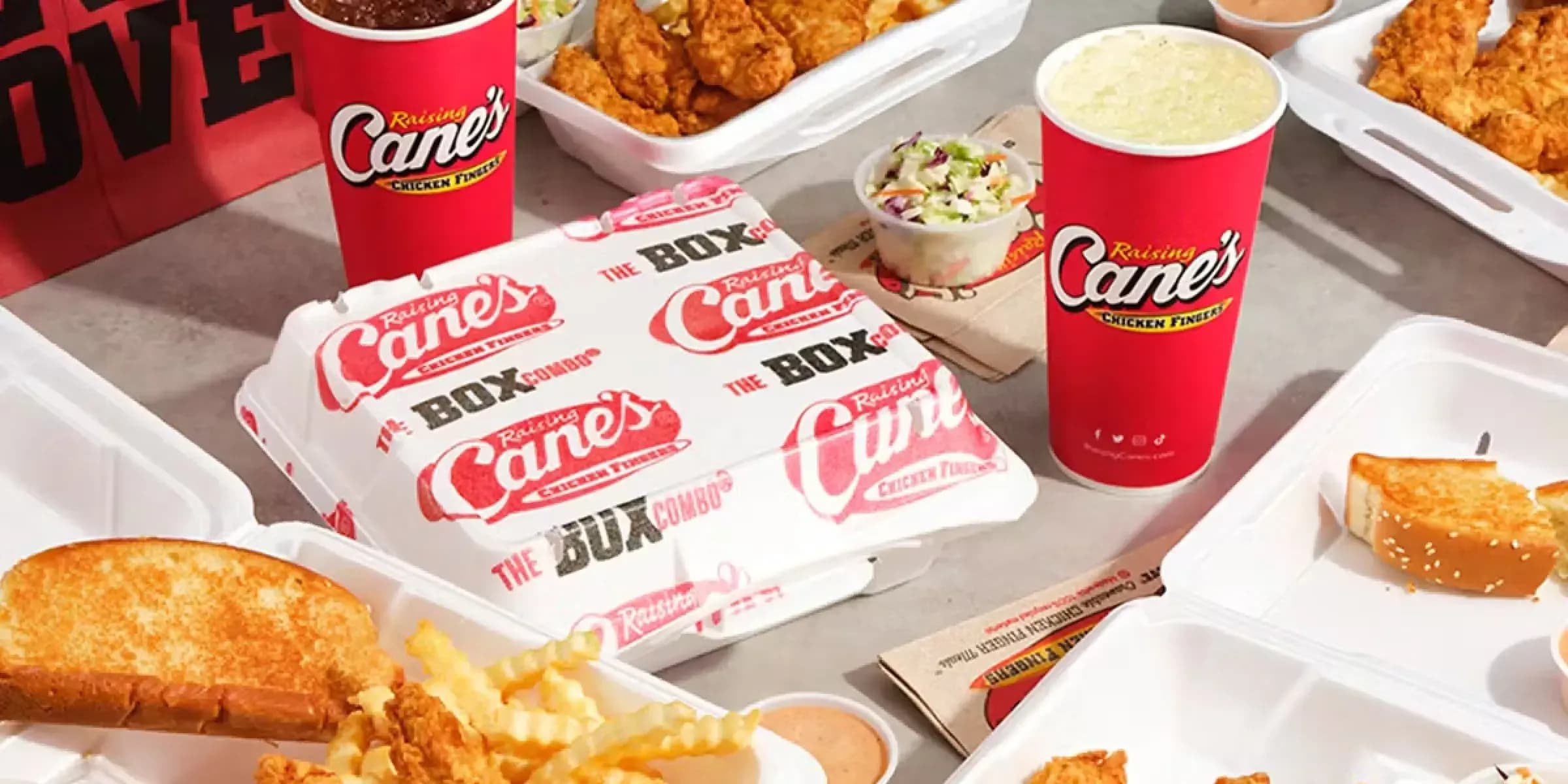 spread of food and food containers on a table, Raising Cane's logo, red and white color palette