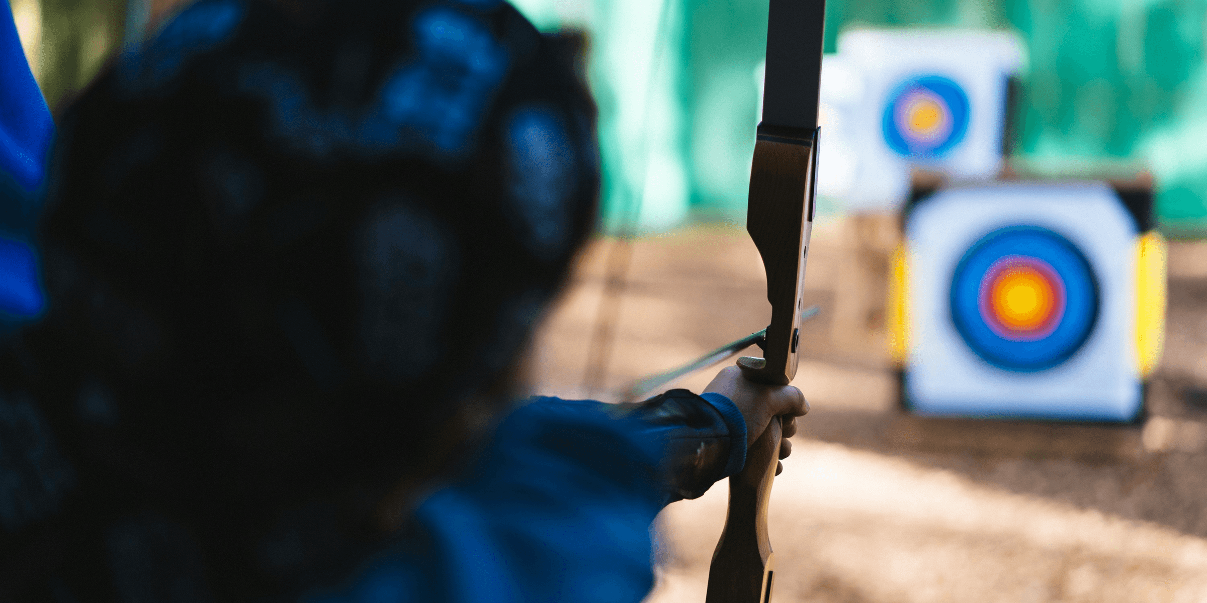 a woman is aiming a bow at a target.