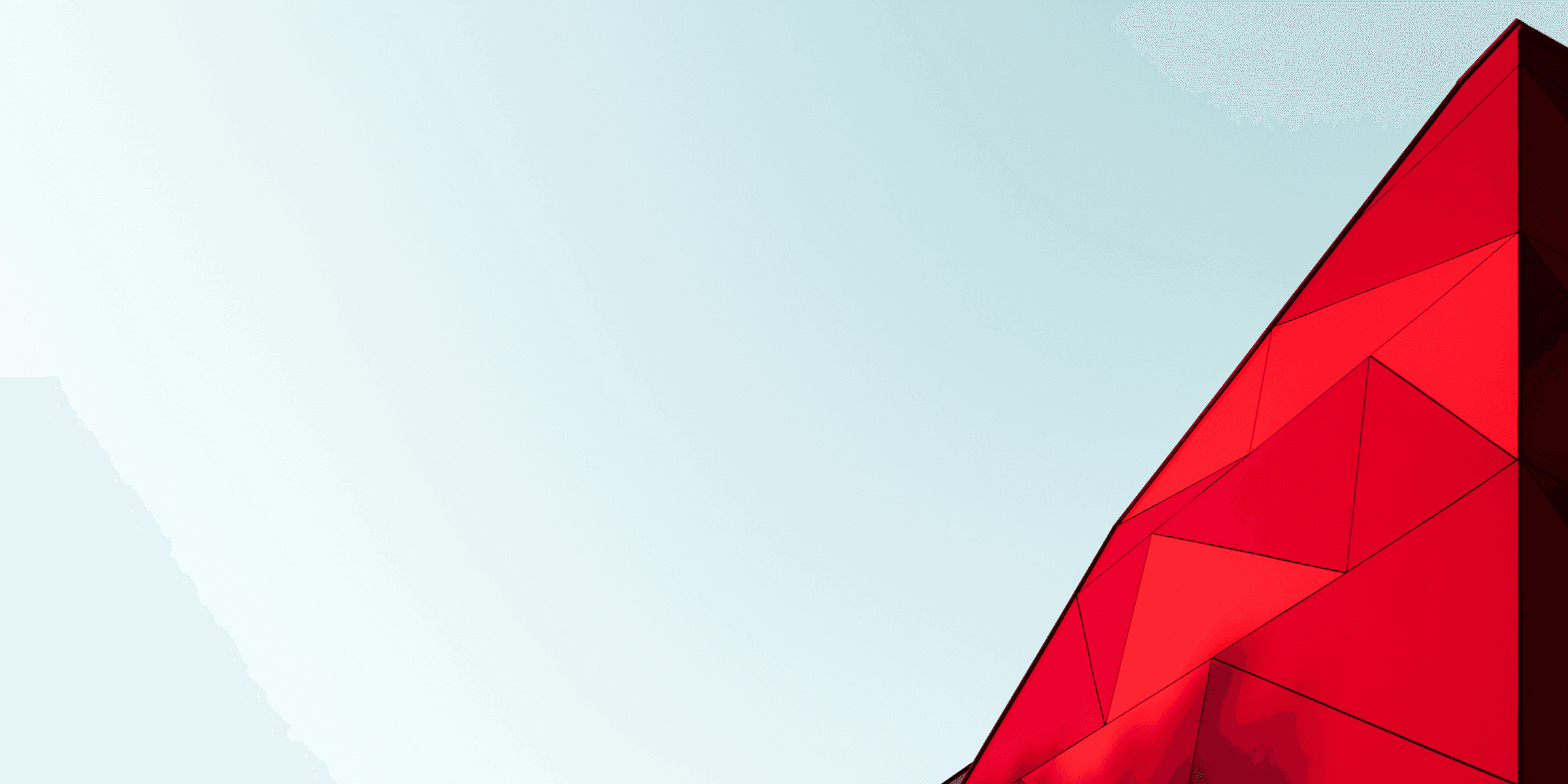 A light blue sky with a bright red, triangular top of a building just visible.