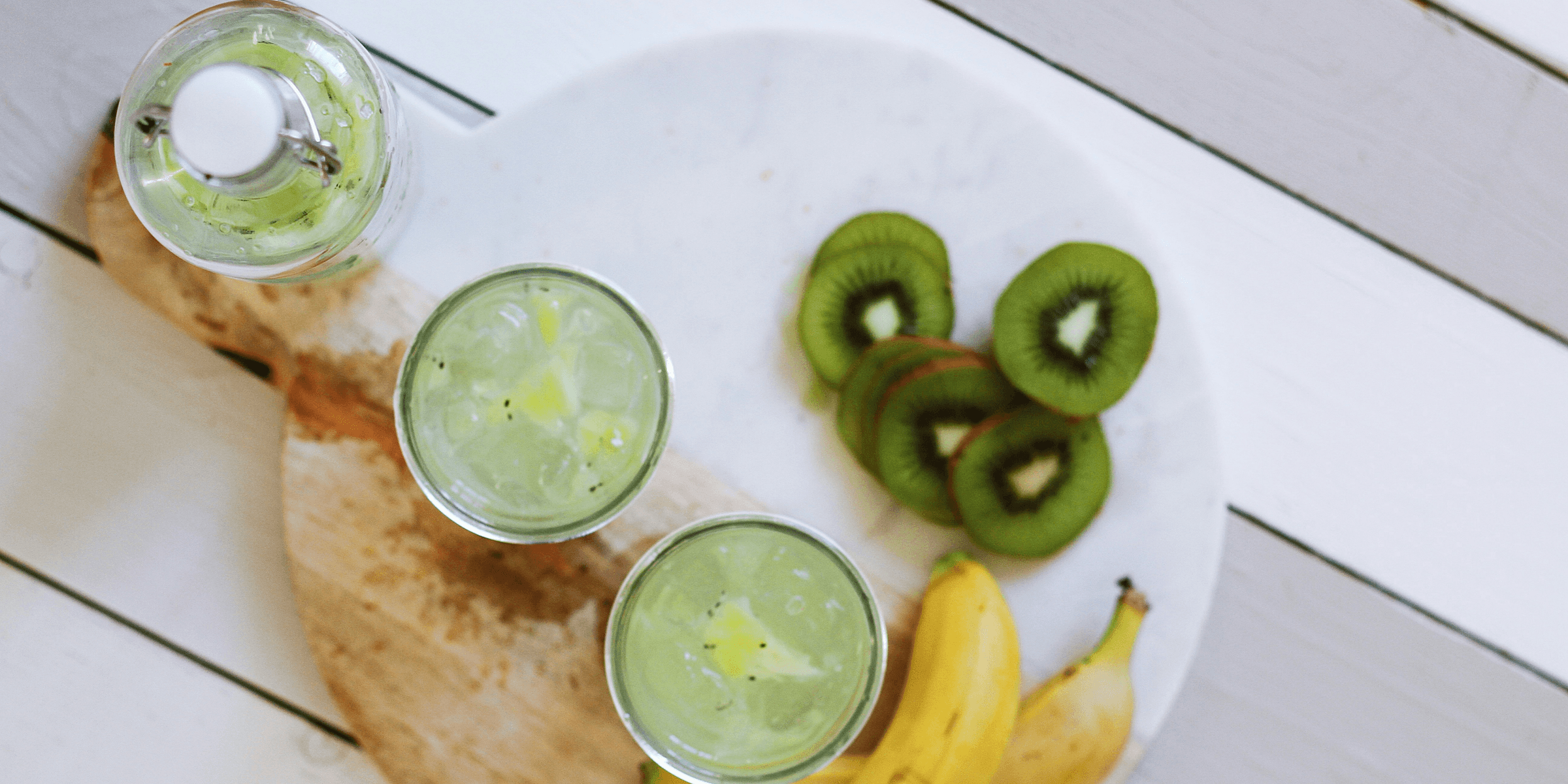 fruit juice cups beside yellow bananas on plate.